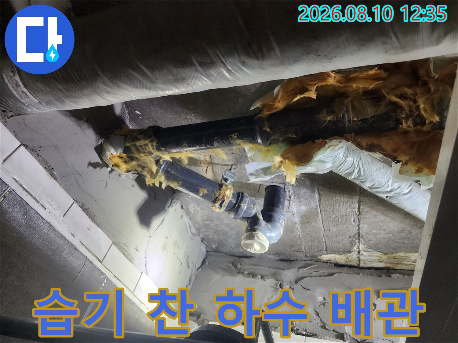 물기가 스며들어 변색된 하수 배관과 찢어진 보온재를 촬영한 사진입니다.