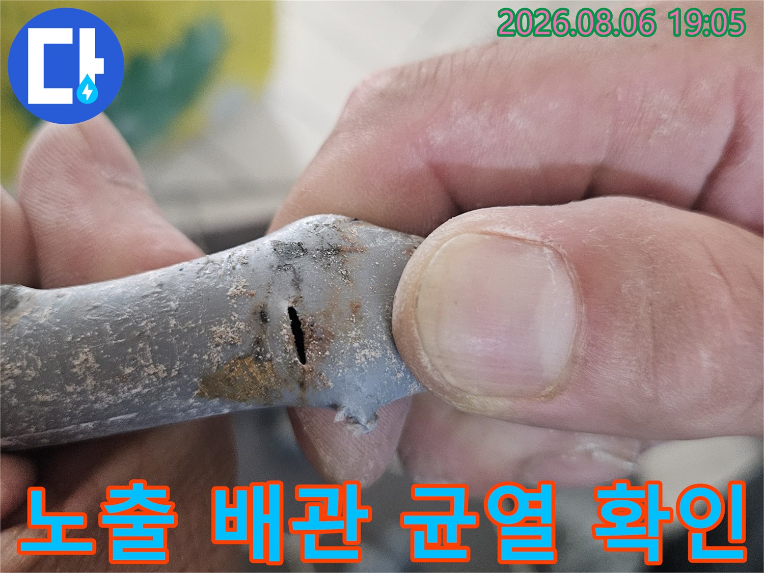 흙과 먼지가 묻은 상태의 노출 배관에서 파손 부위를 강조하여 보여주는 사진