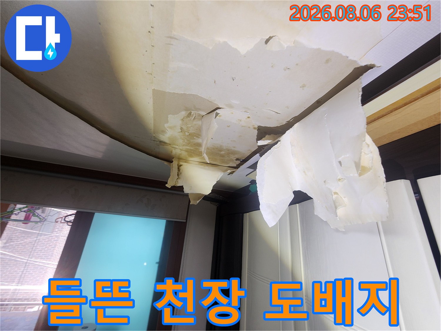 습기로 인해 층이 분리되고 찢어진 상태의 천장 마감재 사진입니다.