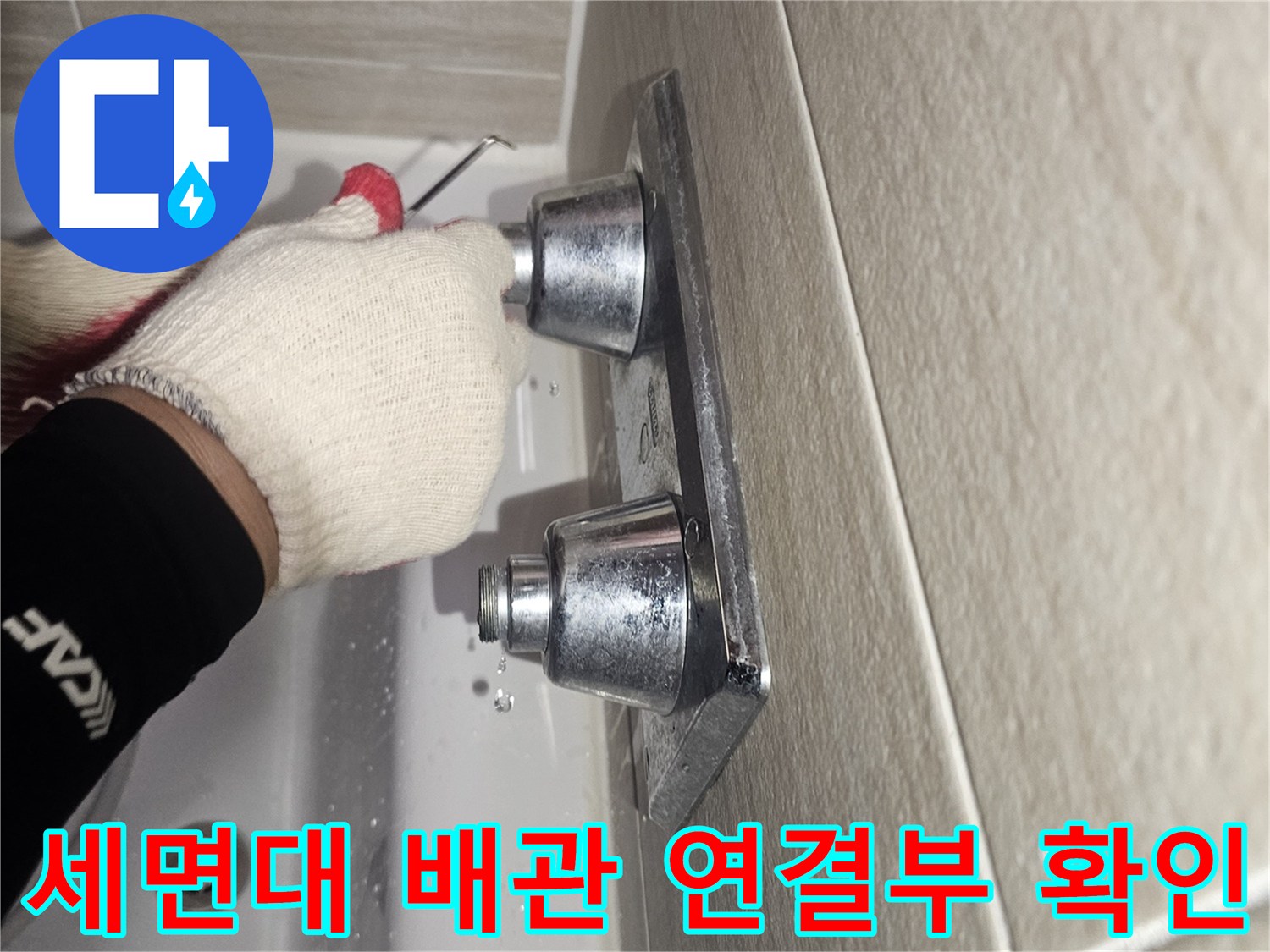 타일 벽면에 설치된 앵글밸브를 점검하는 작업자의 모습