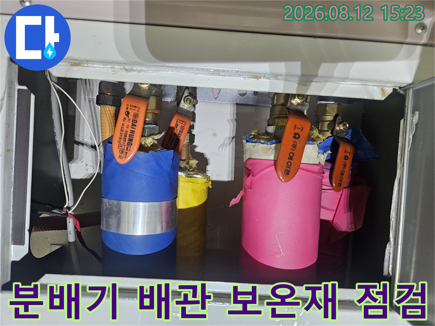 파란색과 분홍색 보온재로 감싸진 배관 밸브들이 나열되어 있는 모습