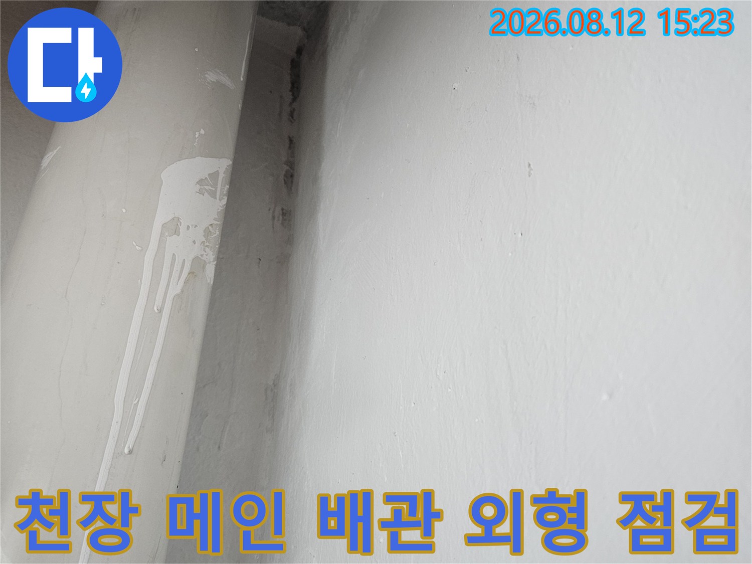 흰색 천장 구석에 설치된 회색 배관의 상태를 찍은 사진