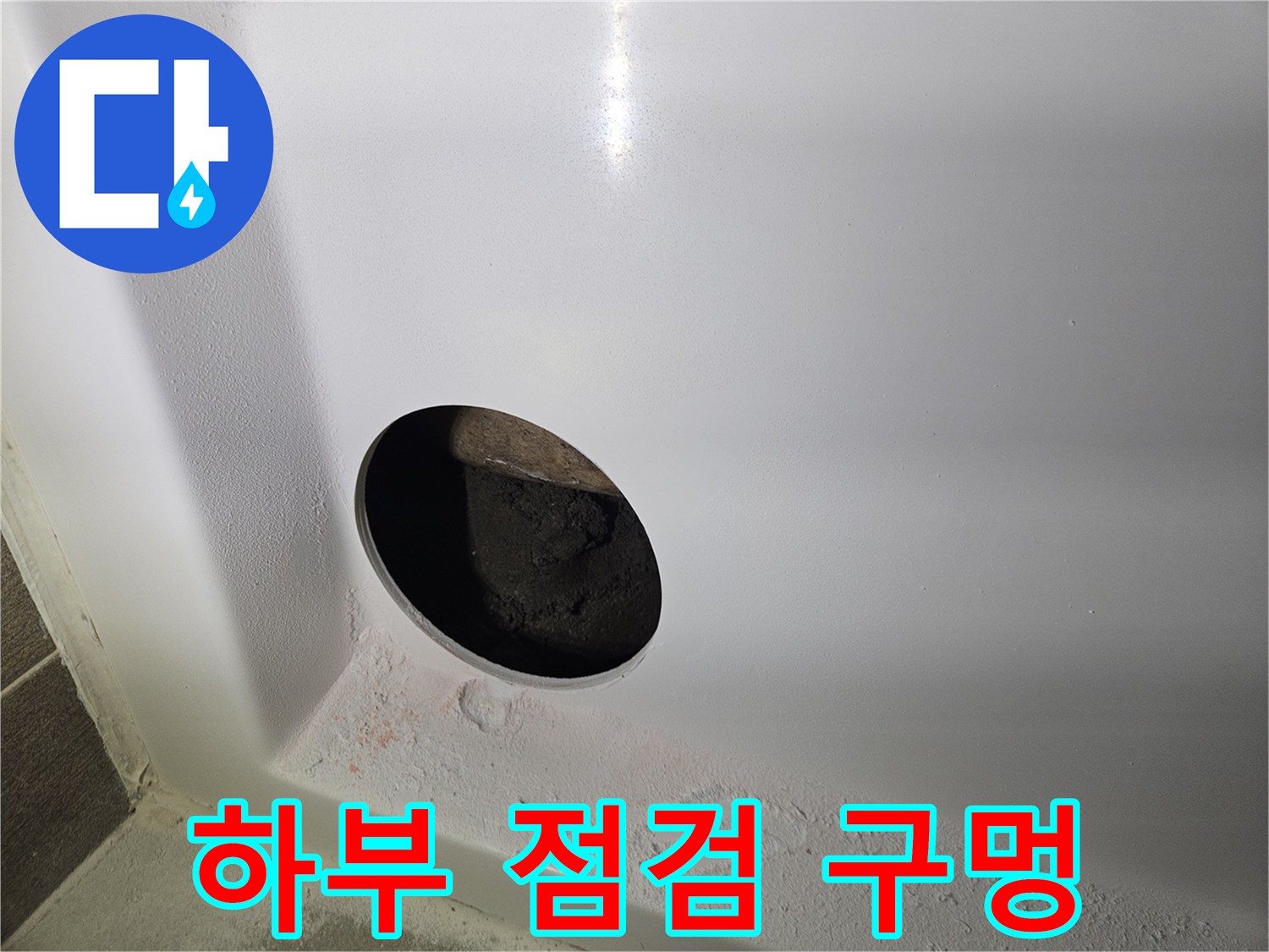 배관 확인을 위해 뚫어놓은 흰색 욕조 패널의 타공 부위