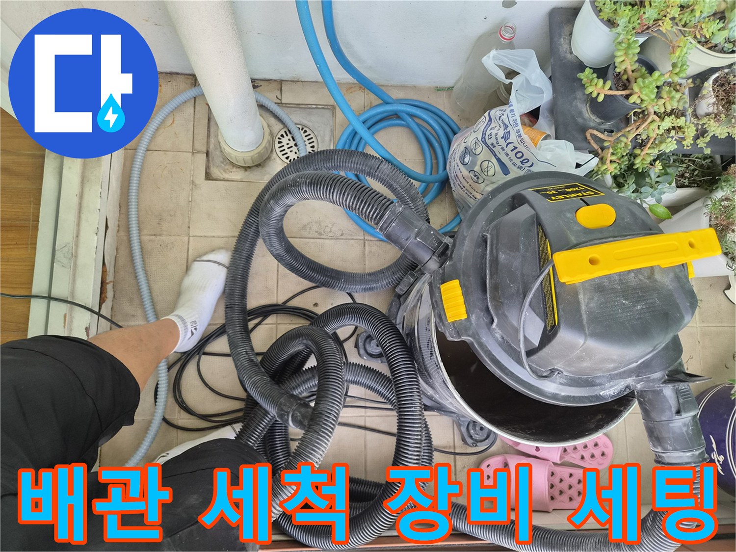 베란다 바닥 타일 위에 놓인 배관 청소용 기계와 호스