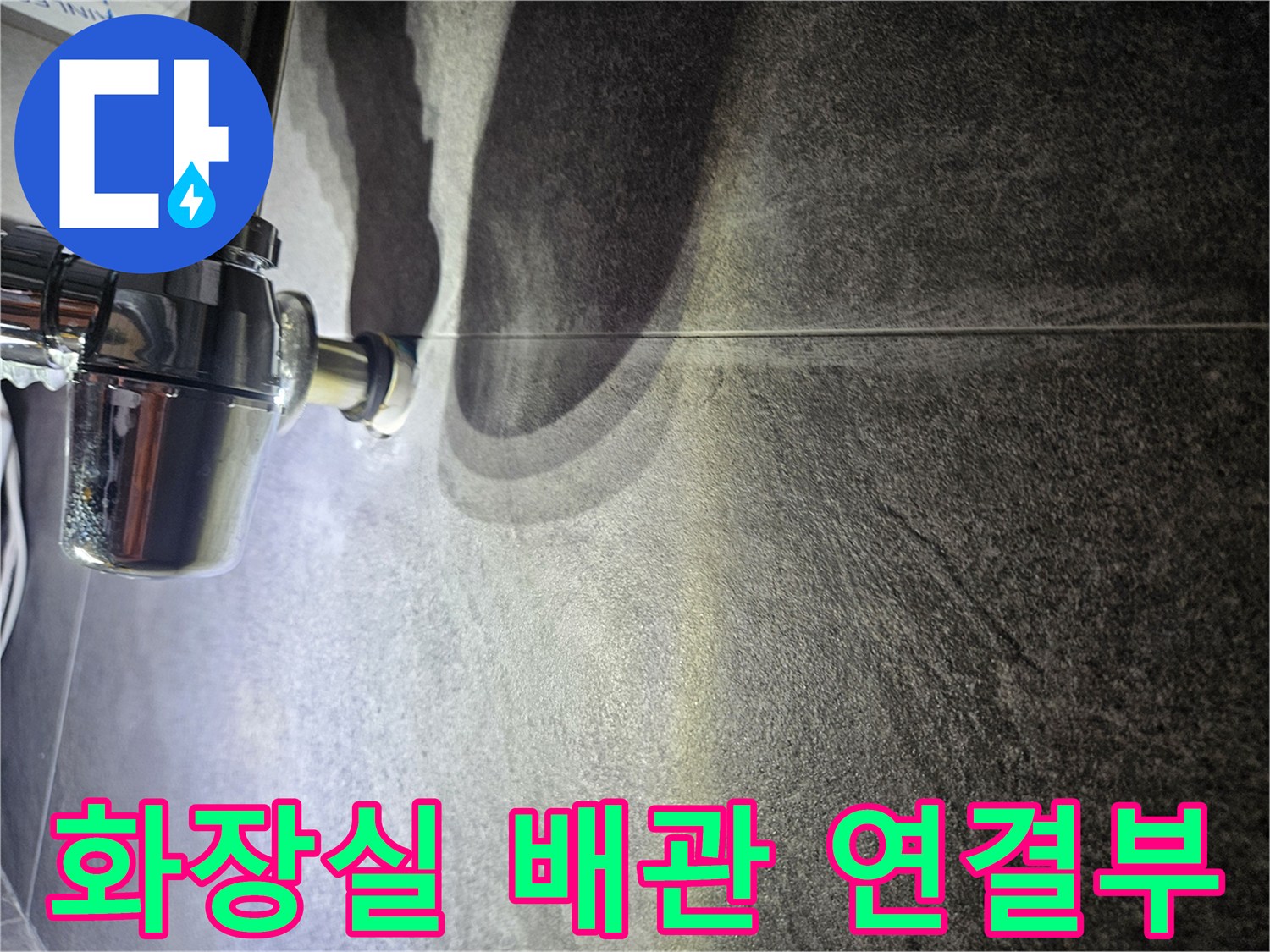 어두운 타일 벽면에 설치된 크롬 도금 배관 부위