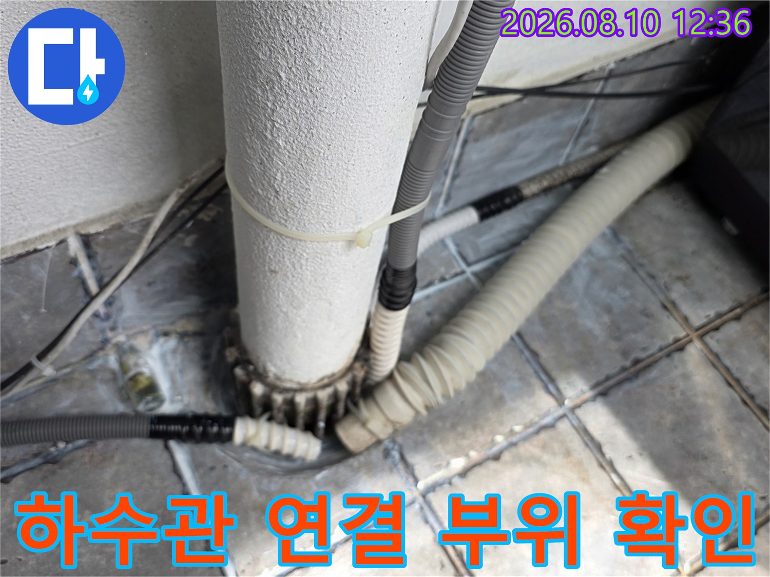 흰색 수직 배관과 연결된 주름진 호스의 상세한 모습