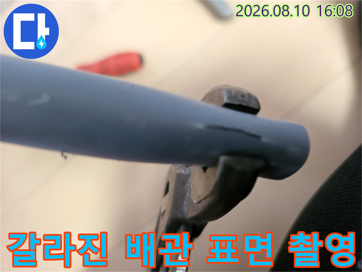 파란색 배층 배관에 발생한 미세한 갈라짐을 찍은 사진입니다.