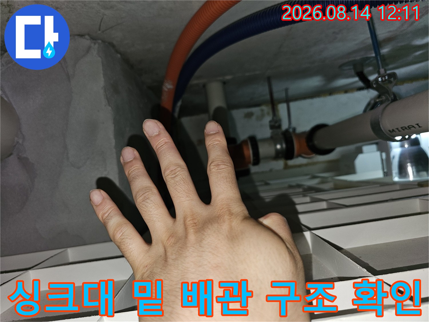 싱크대 하부 천장 내부의 오렌지색 및 파란색 주름관 연결 부위