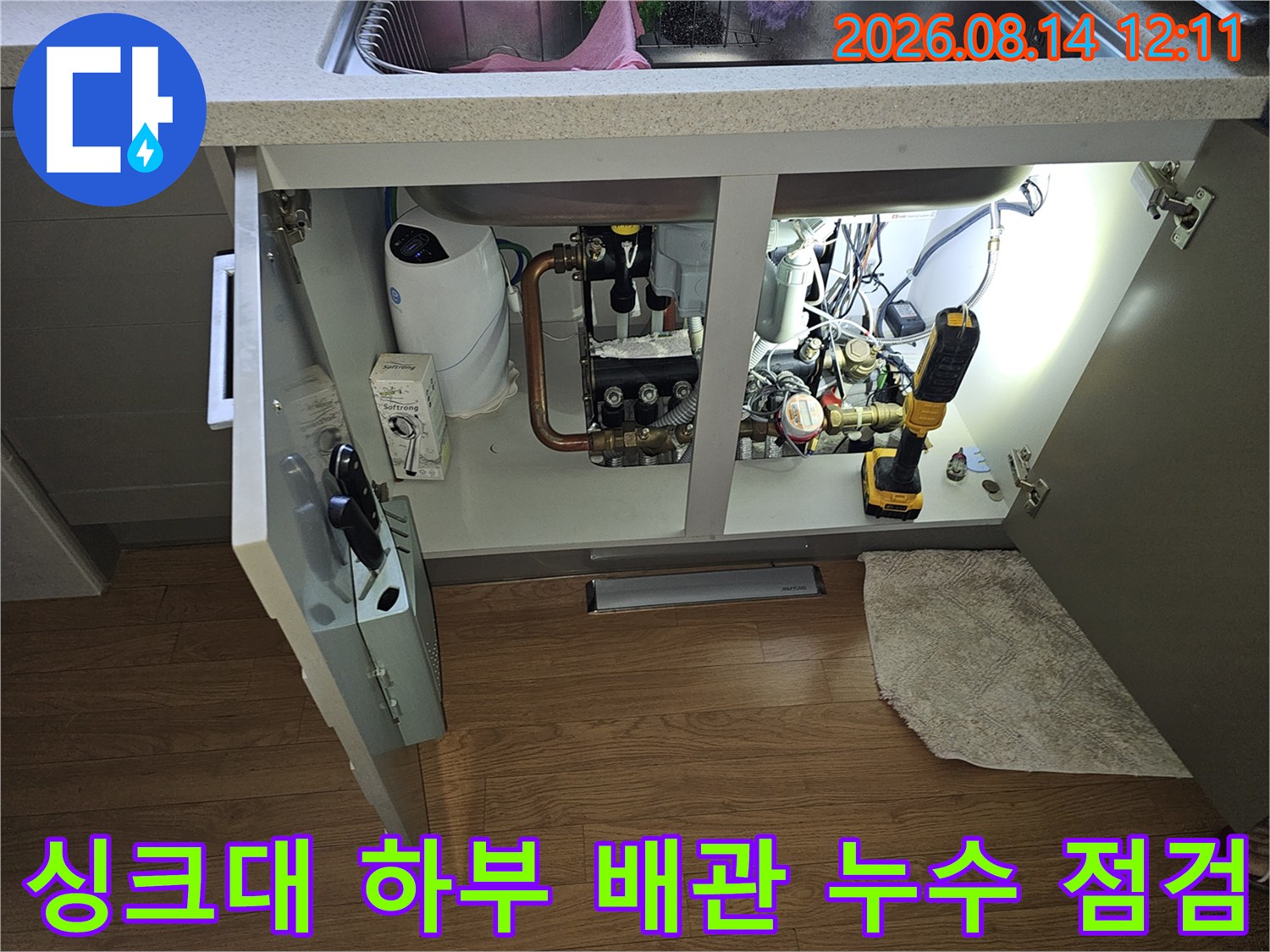싱크대 하부장 내 수도 계량기와 연결된 다양한 배관들의 모습