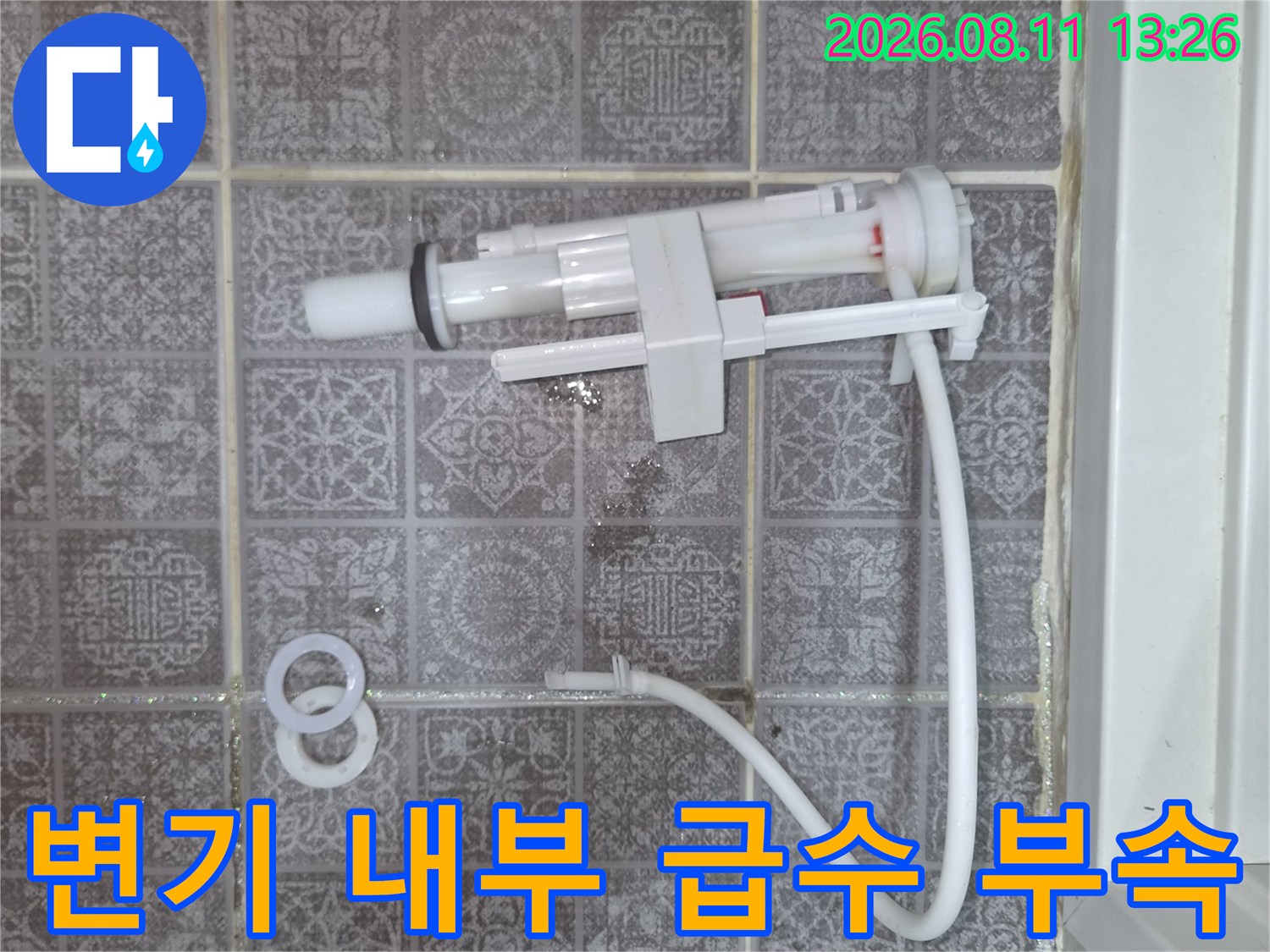 타일 벽면에 설치된 변기 급수 밸브와 호스 상세 이미지