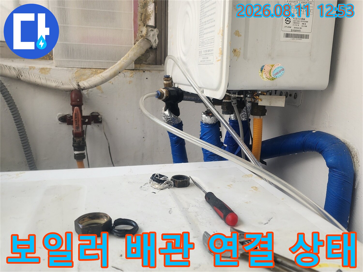 파란색 보온재가 씌워진 보일러 배관의 연결 부위를 관찰하는 장면입니다.
