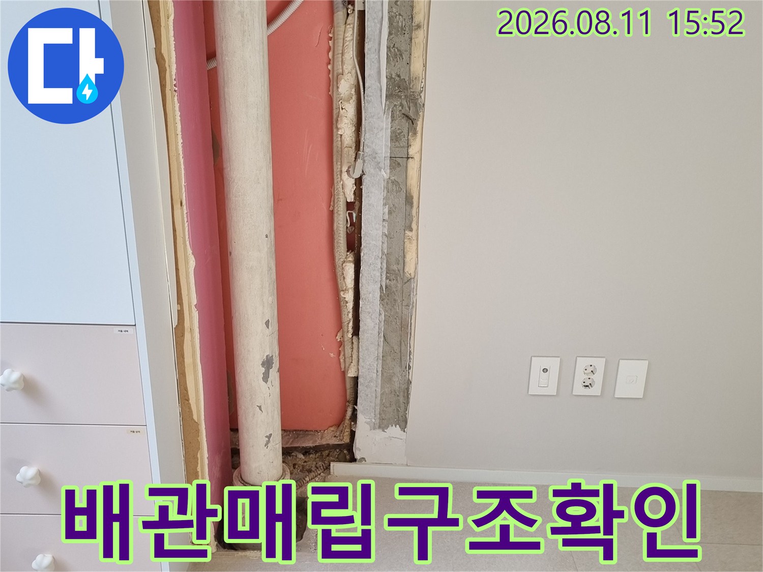 벽면의 일부를 걷어내어 드러난 분홍색 단열재와 수평 배관 그리고 에어컨 호스의 배치 상태
