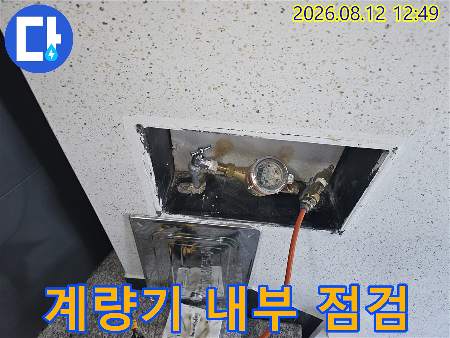 벽면 타공 부위로 보이는 수도 계량기와 배관 연결 장치