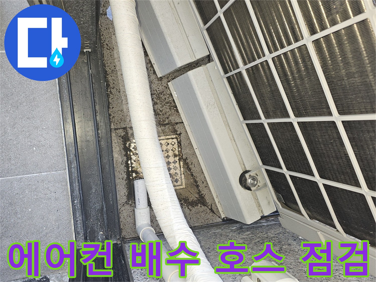 실외기 냉각핀 아래쪽으로 연결된 하얀색 드레인 호스 모습입니다.