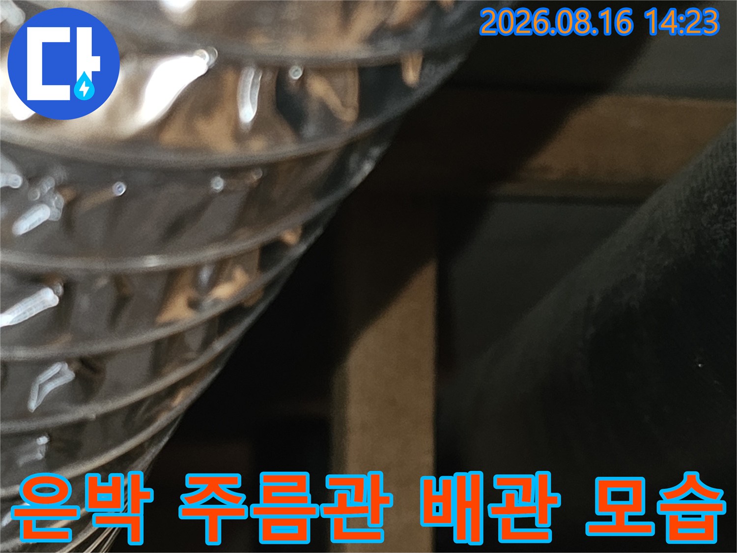 천장에 설치된 은색 주름관과 검은색 배관의 근접 촬영입니다.