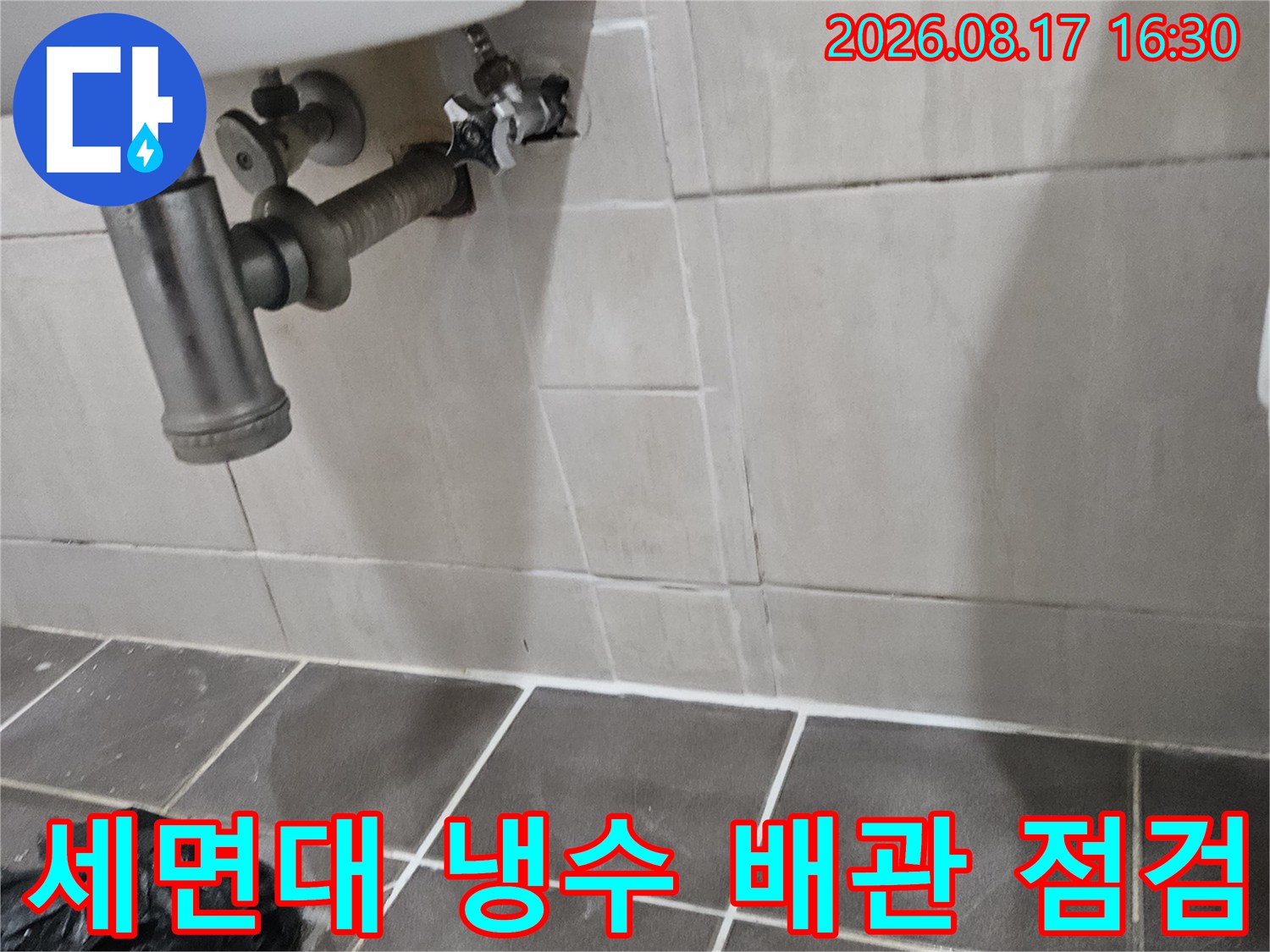 세면대 아래쪽 수도 연결 부위와 타일 벽면 사진