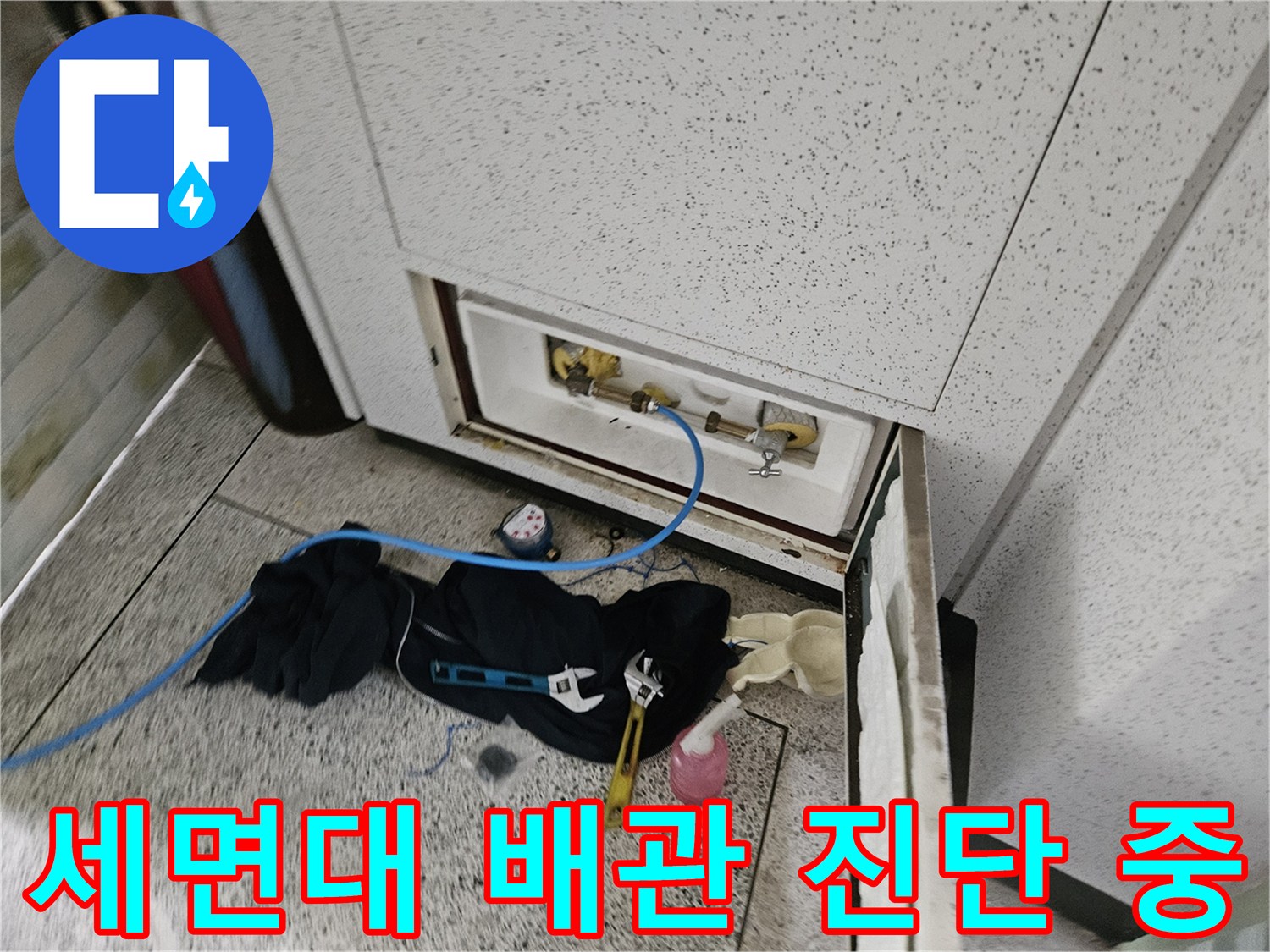 세면대 하부의 앵글밸브와 직수 배관을 정밀하게 검사하는 장면입니다.