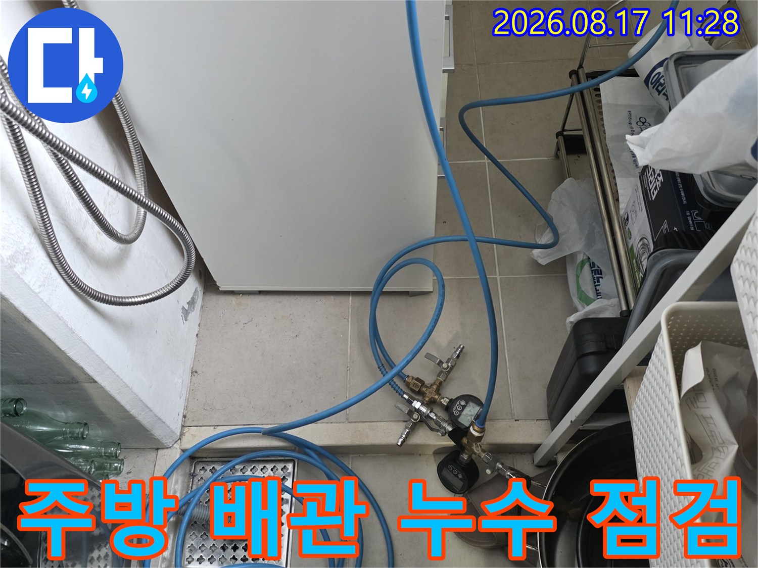 싱크대 하부의 파란 호스와 연결된 배관 및 검사 도구들