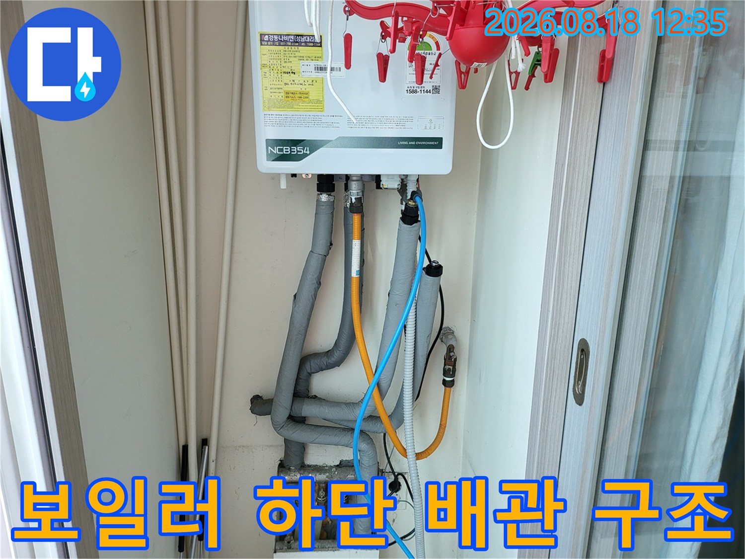 회색 배관과 유색 호스가 연결된 보일러 아래쪽 설비 모습입니다.