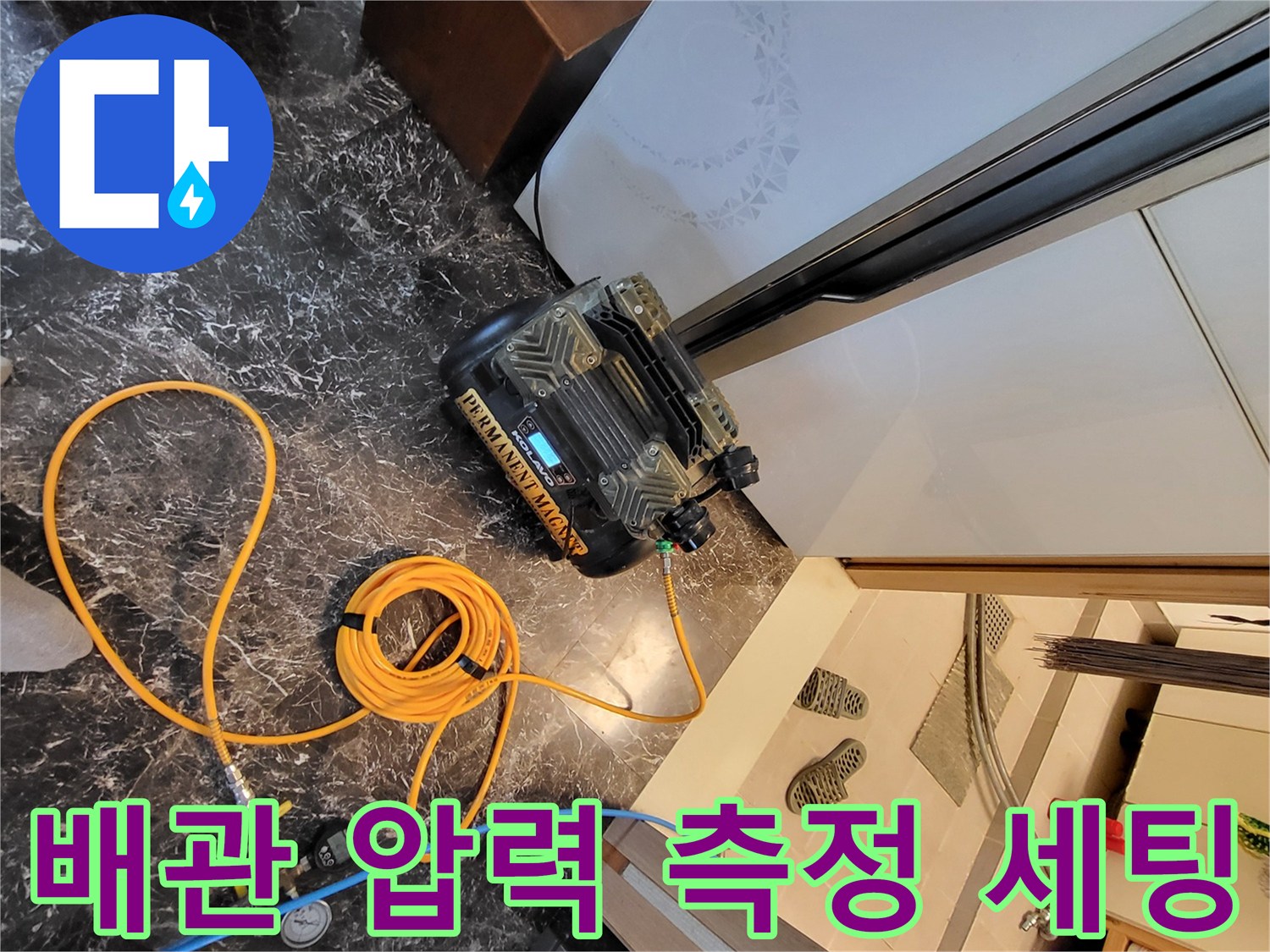 바닥 타일 위에 놓인 공압 검사용 컴프레서와 연결 호스