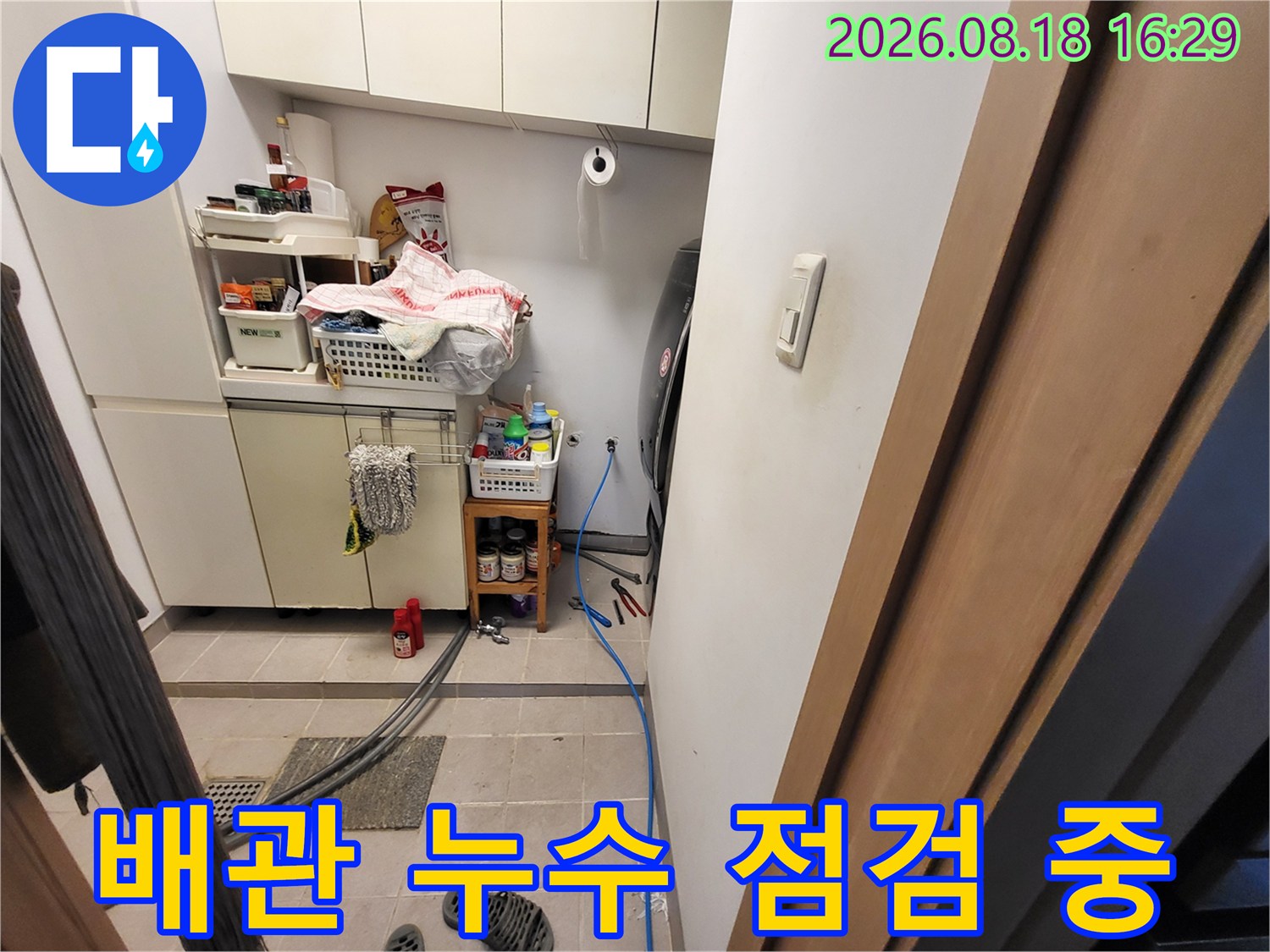 세면대 아래쪽 좁은 공간에 위치한 수도 배관 및 연결 부속품