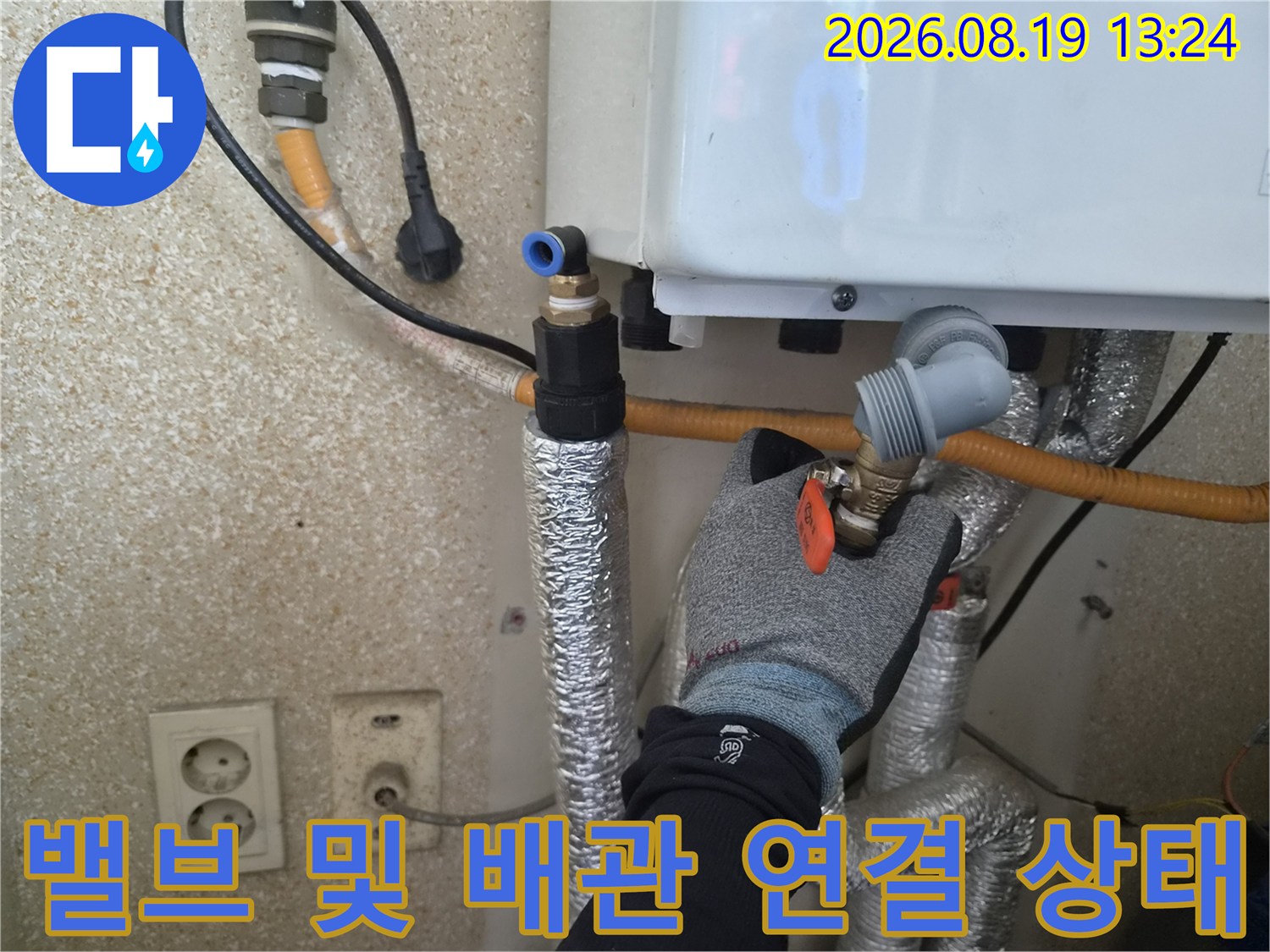 장갑을 낀 작업자가 보일러 하단 밸브와 배관의 체결 상태를 점검합니다.