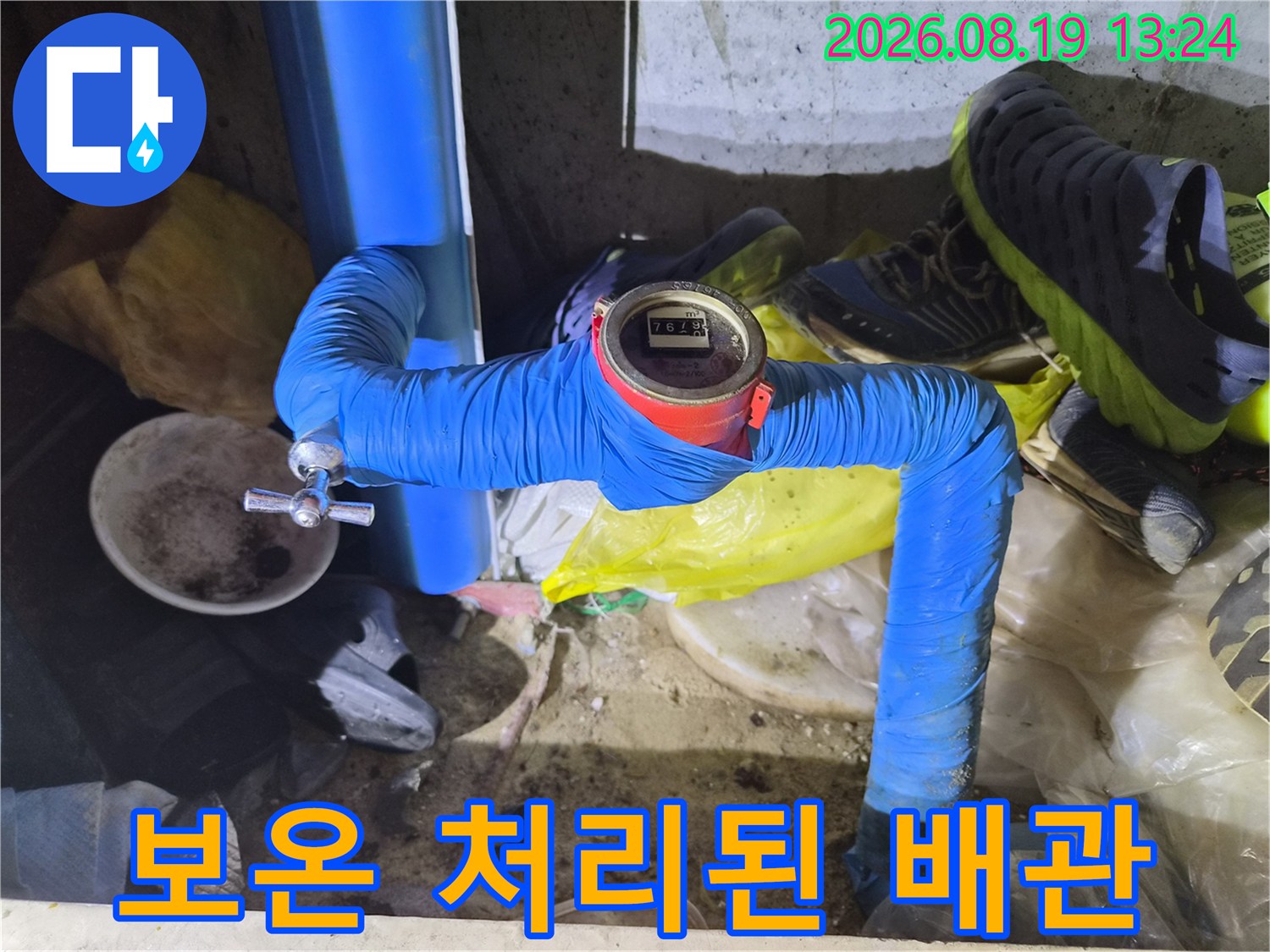 파란색 보온재로 감싸진 수도 배관과 수치가 표시된 계량기 장치입니다.