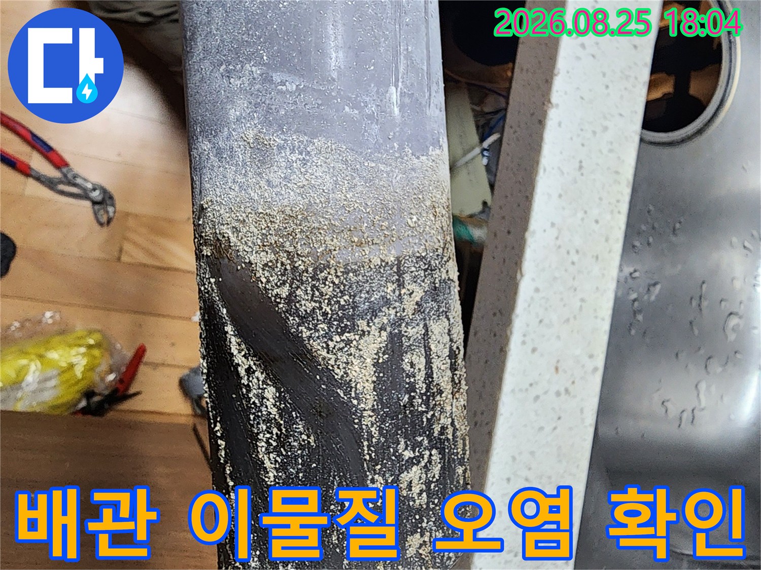 오염된 배수관 표면과 주변의 습한 상태를 촬영한 사진
