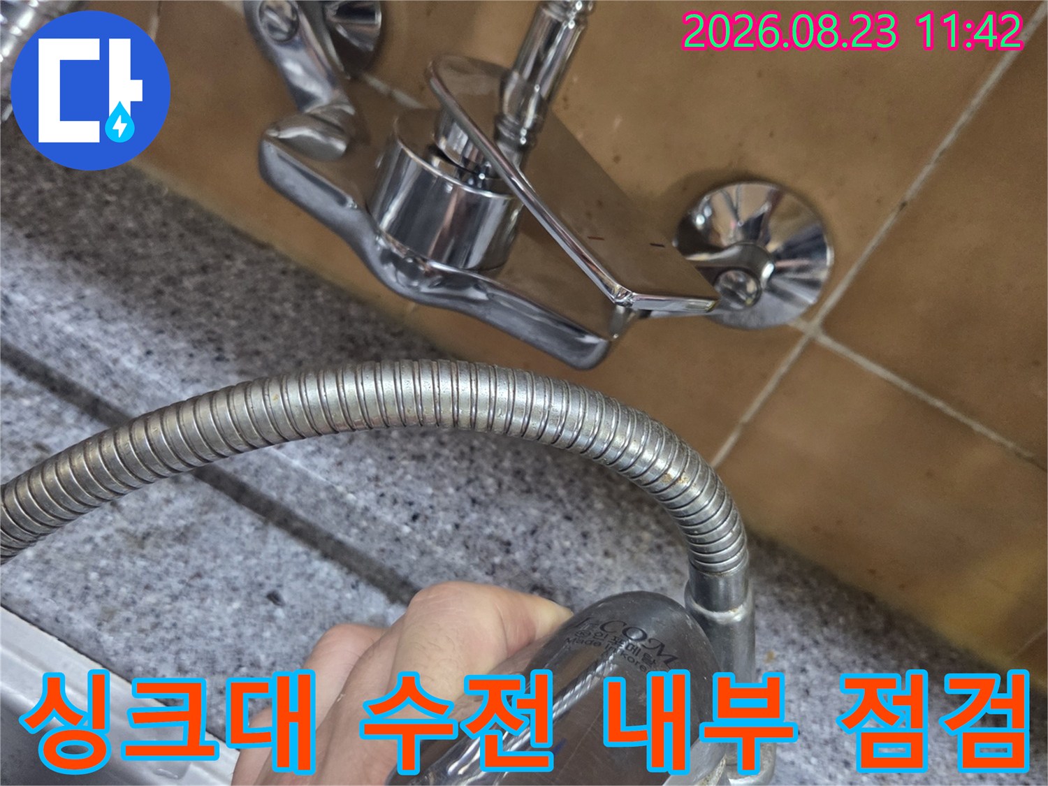 손으로 잡고 있는-싱크대 수전 헤드와 연결 호스 부분입니다.
