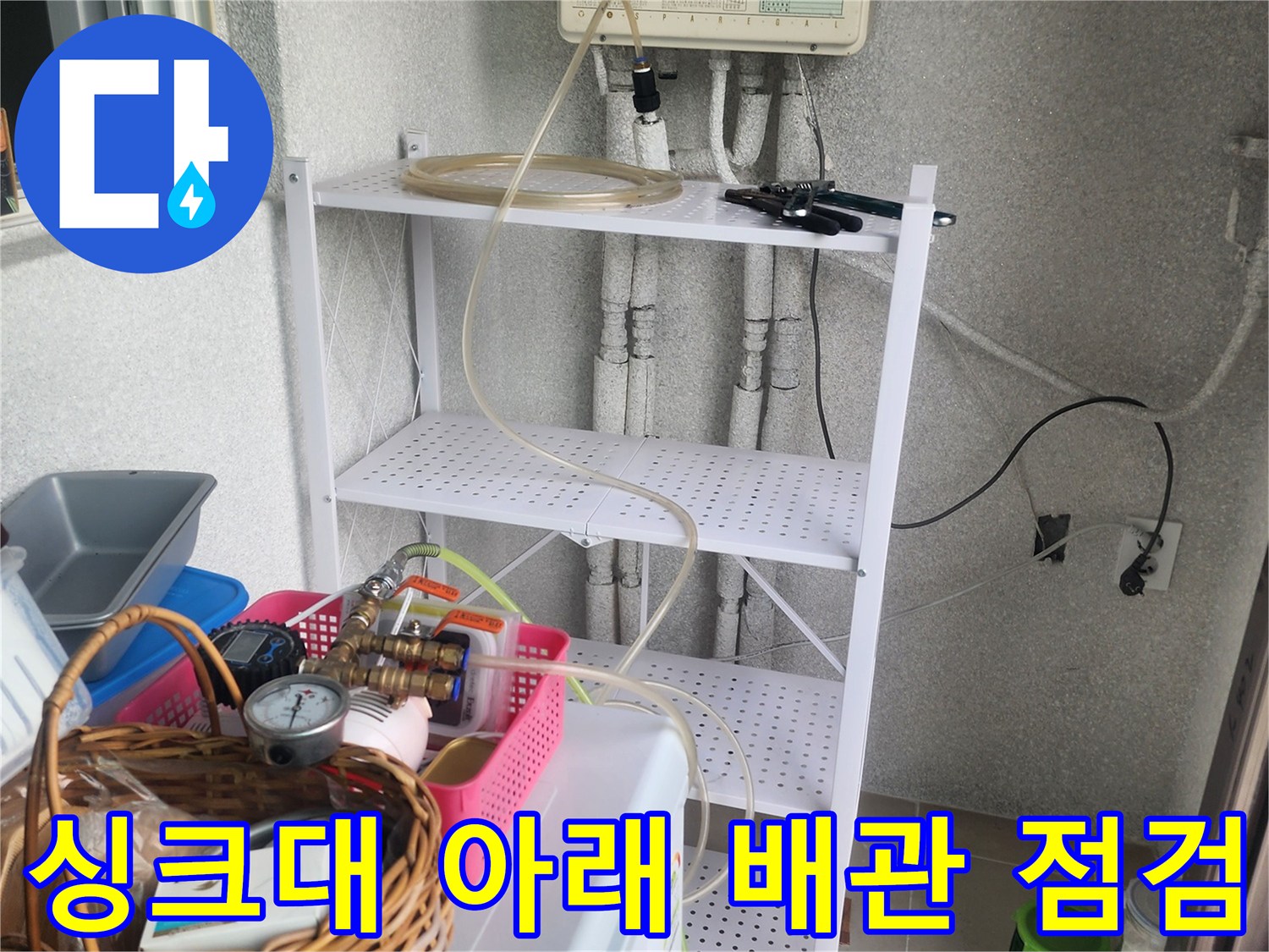 복잡하게 연결된 싱크대 하부 배관과 작업용 압력계 및 도구들