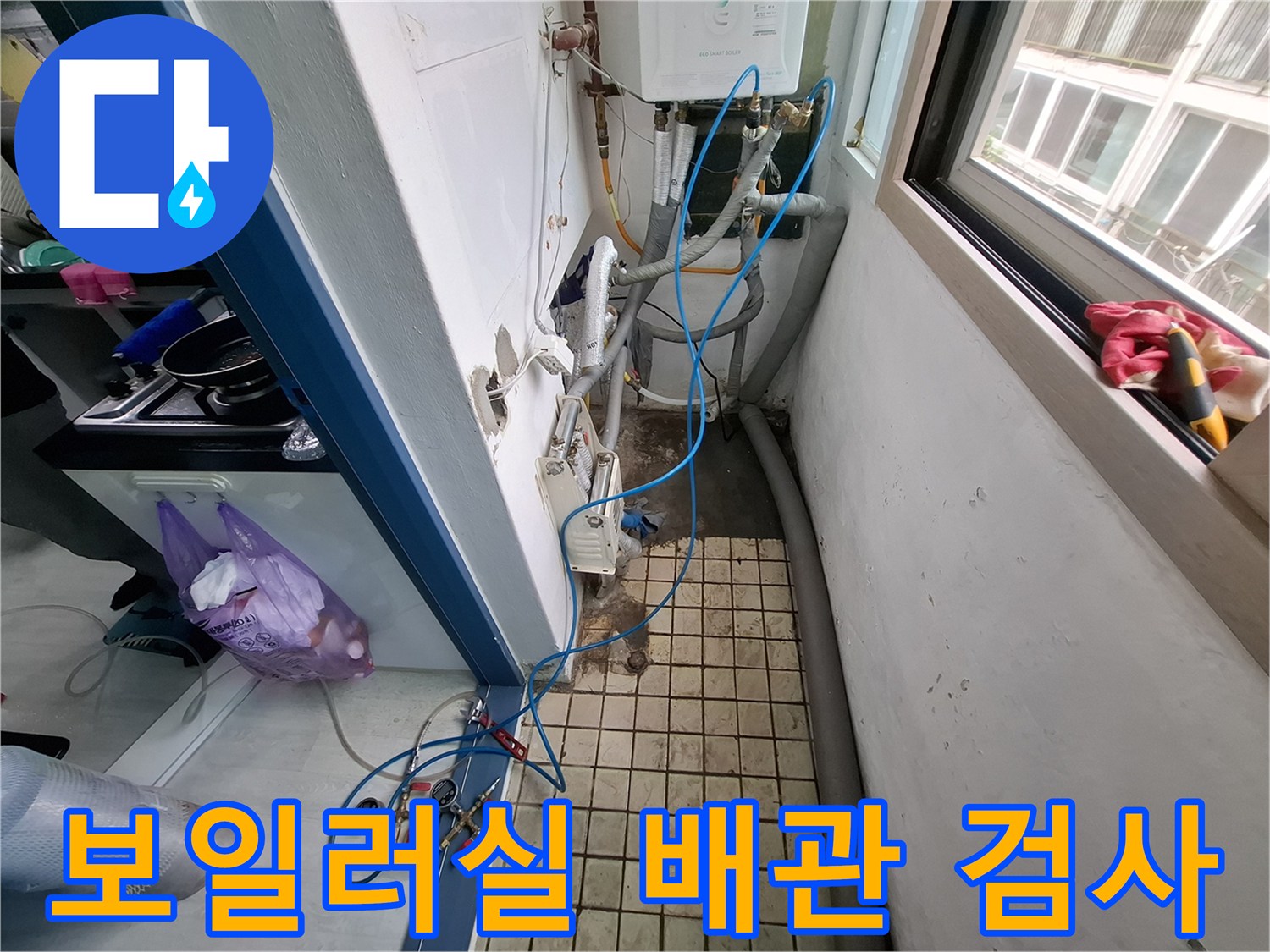 바닥 타일 옆으로 길게 늘어진 파란색 배관 점검용 호스