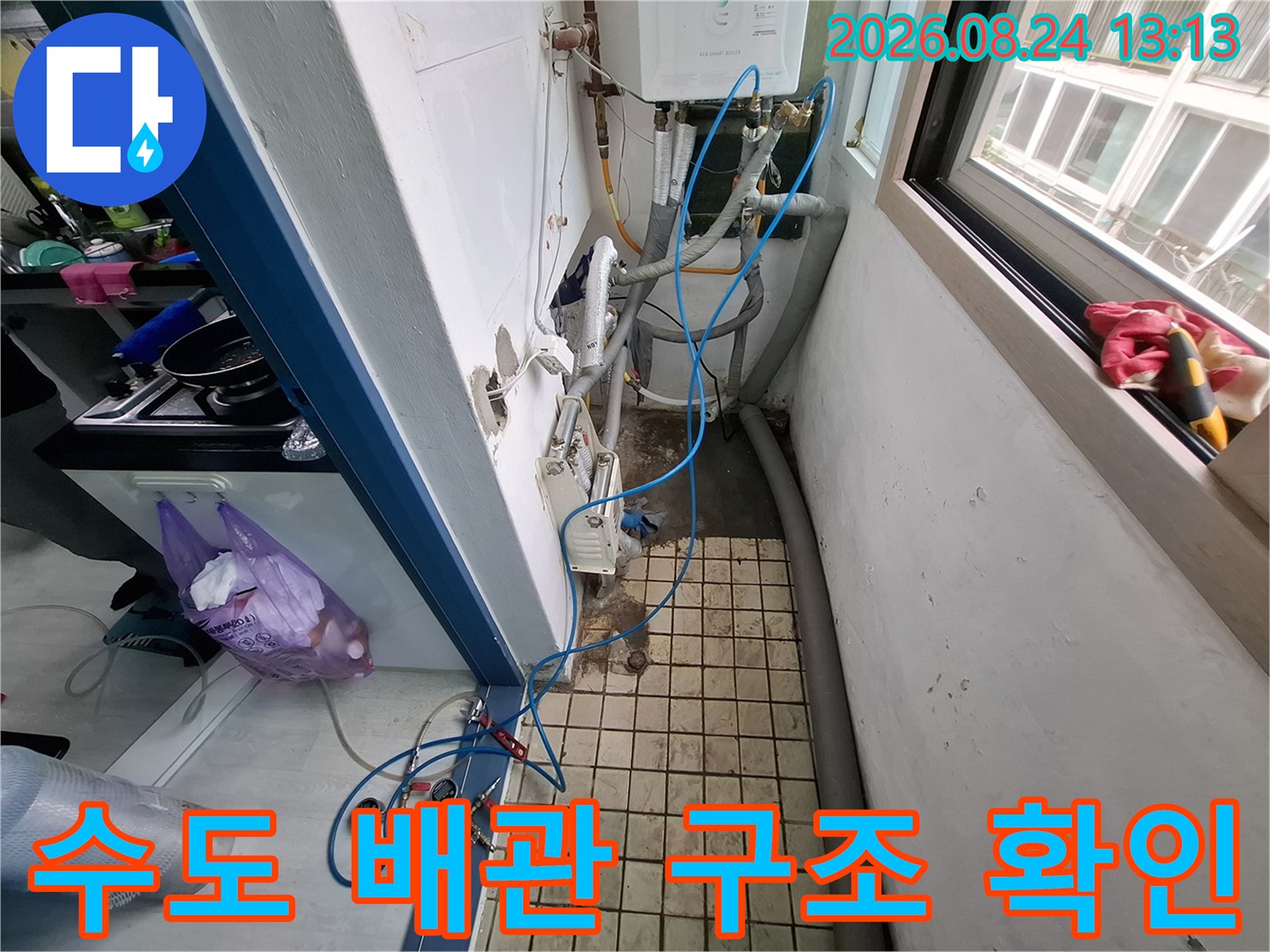 복잡하게 얽힌 수도 배관과 보일러실의 설비 상태를 보여주는 사진입니다.