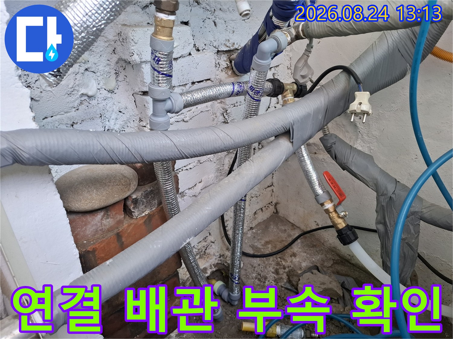 은색 보온재와 파란색 호스가 연결된 배관의 상태를 근거리에서 촬영하였습니다.