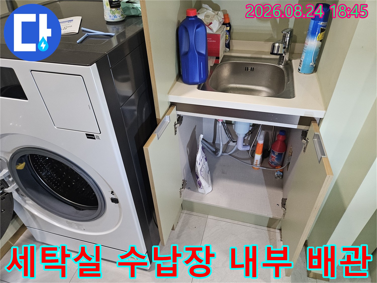세탁기 옆 하부 공간-배관과 세제 용기가 보이는 모습