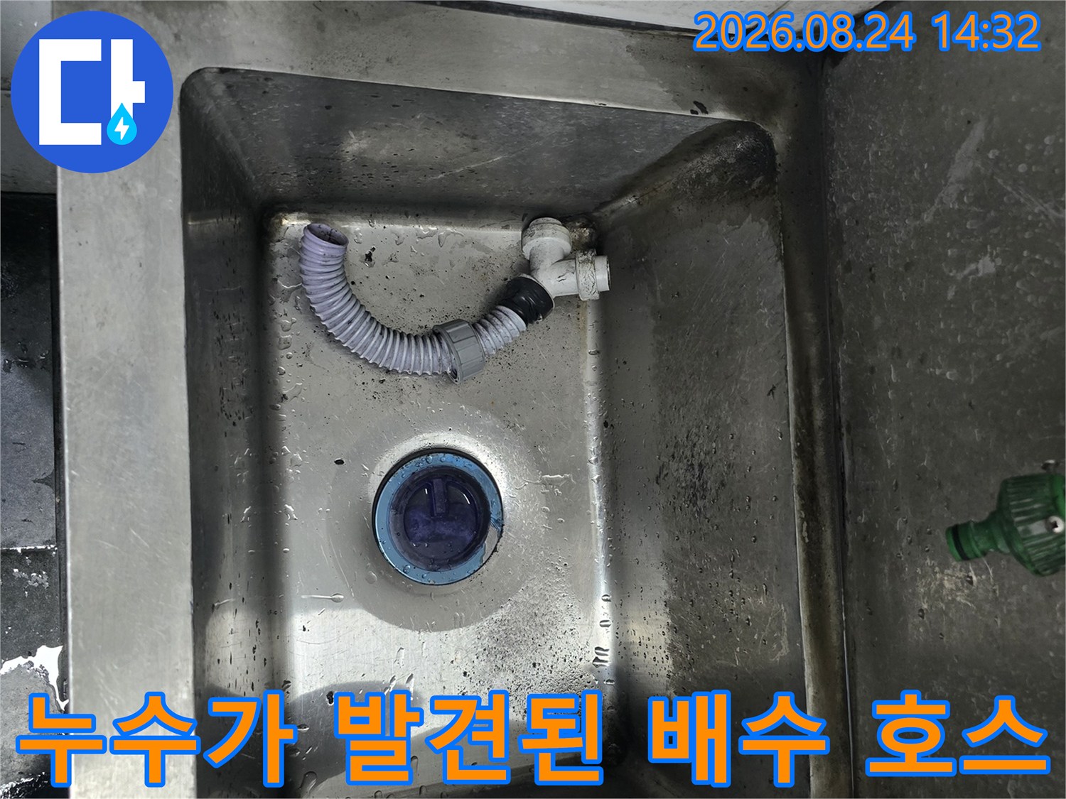 물기가 맺힌 스테인리스 싱크대와 연결된 흰색 주름식 배수관