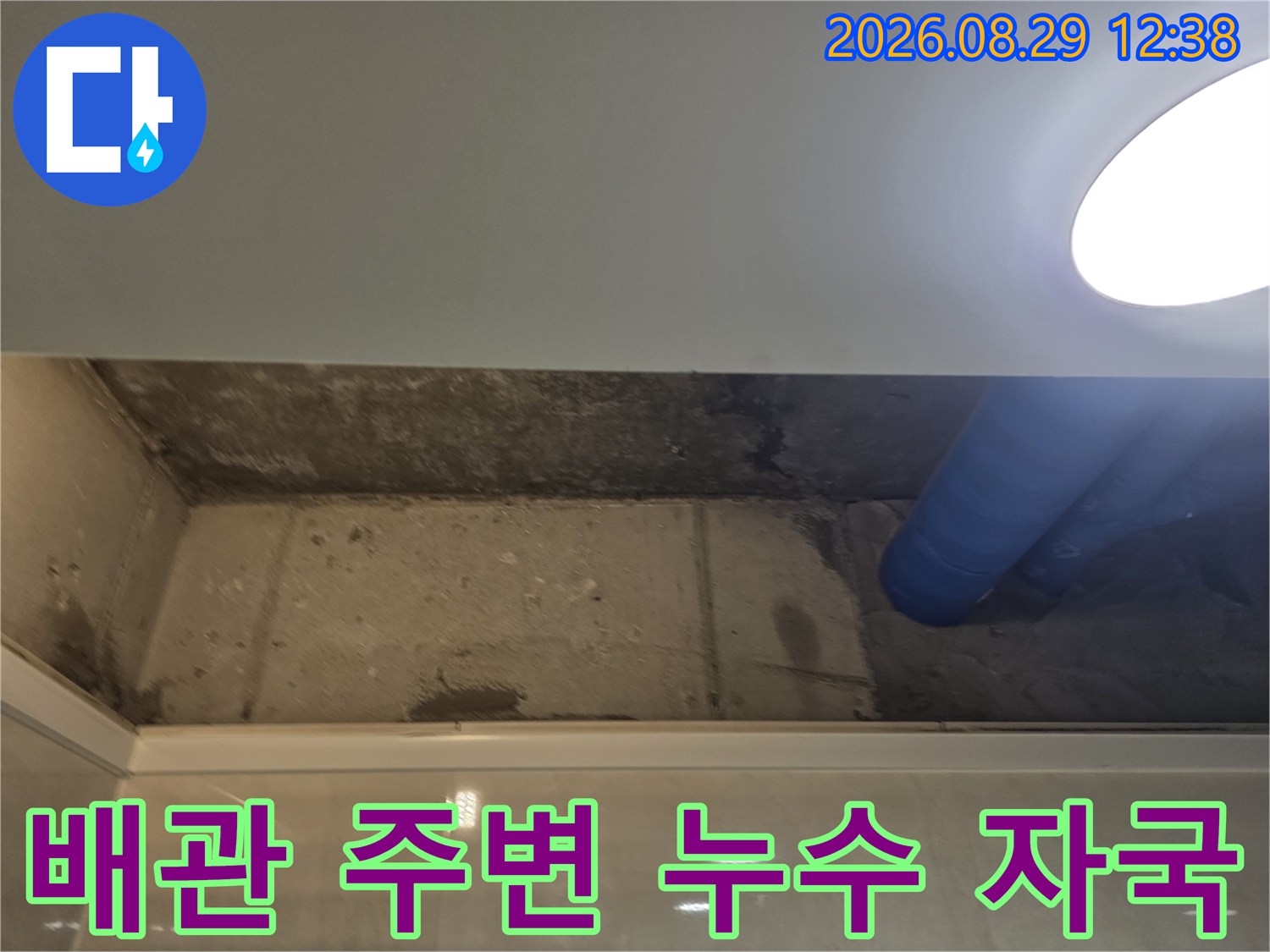 파란색 배관 옆으로-물에 젖어 얼룩진 천장 면의 모습입니다.