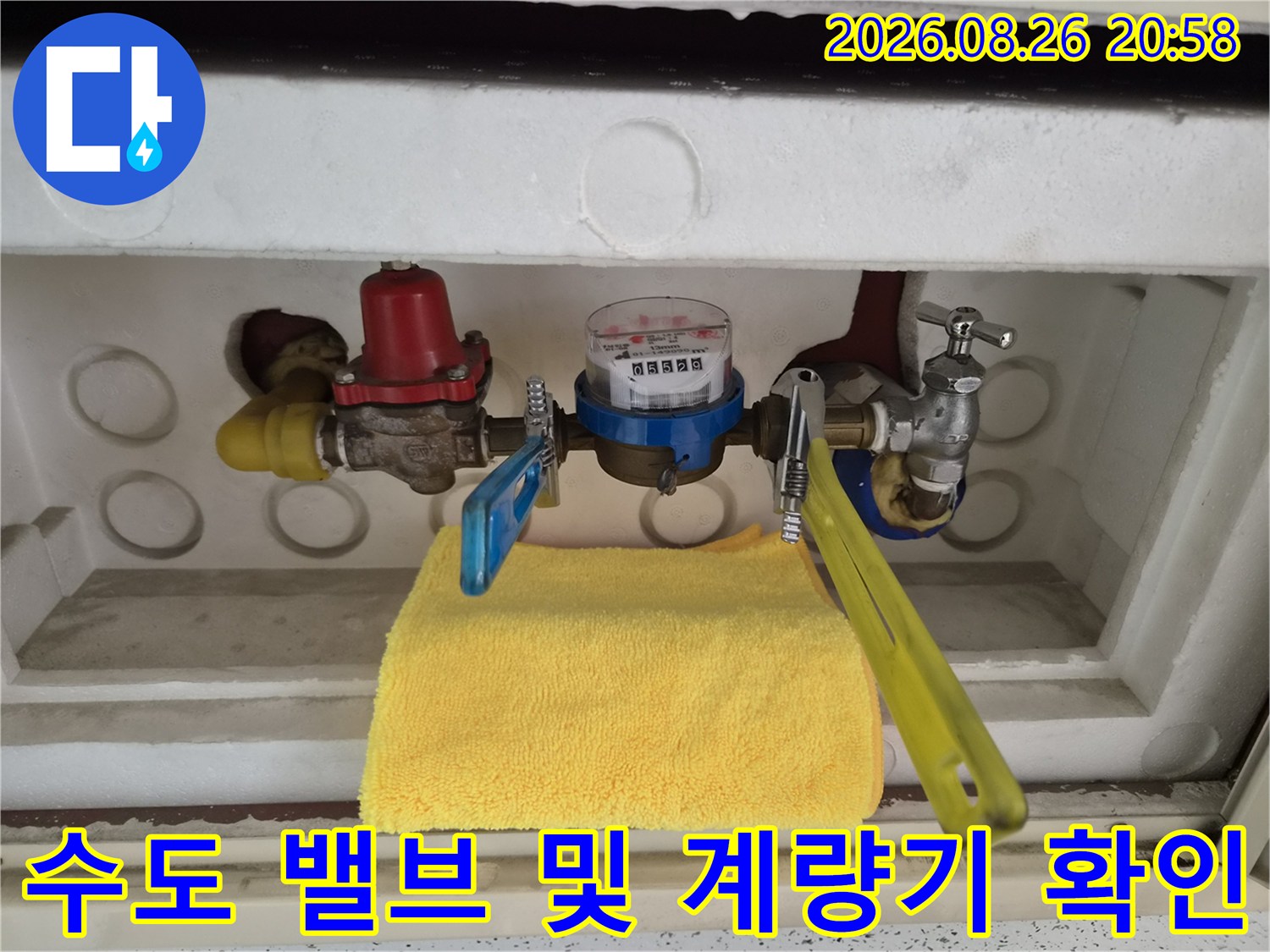 노란색 레버가 달린 수도 밸브와 계량기 수치 표시창의 모습입니다.