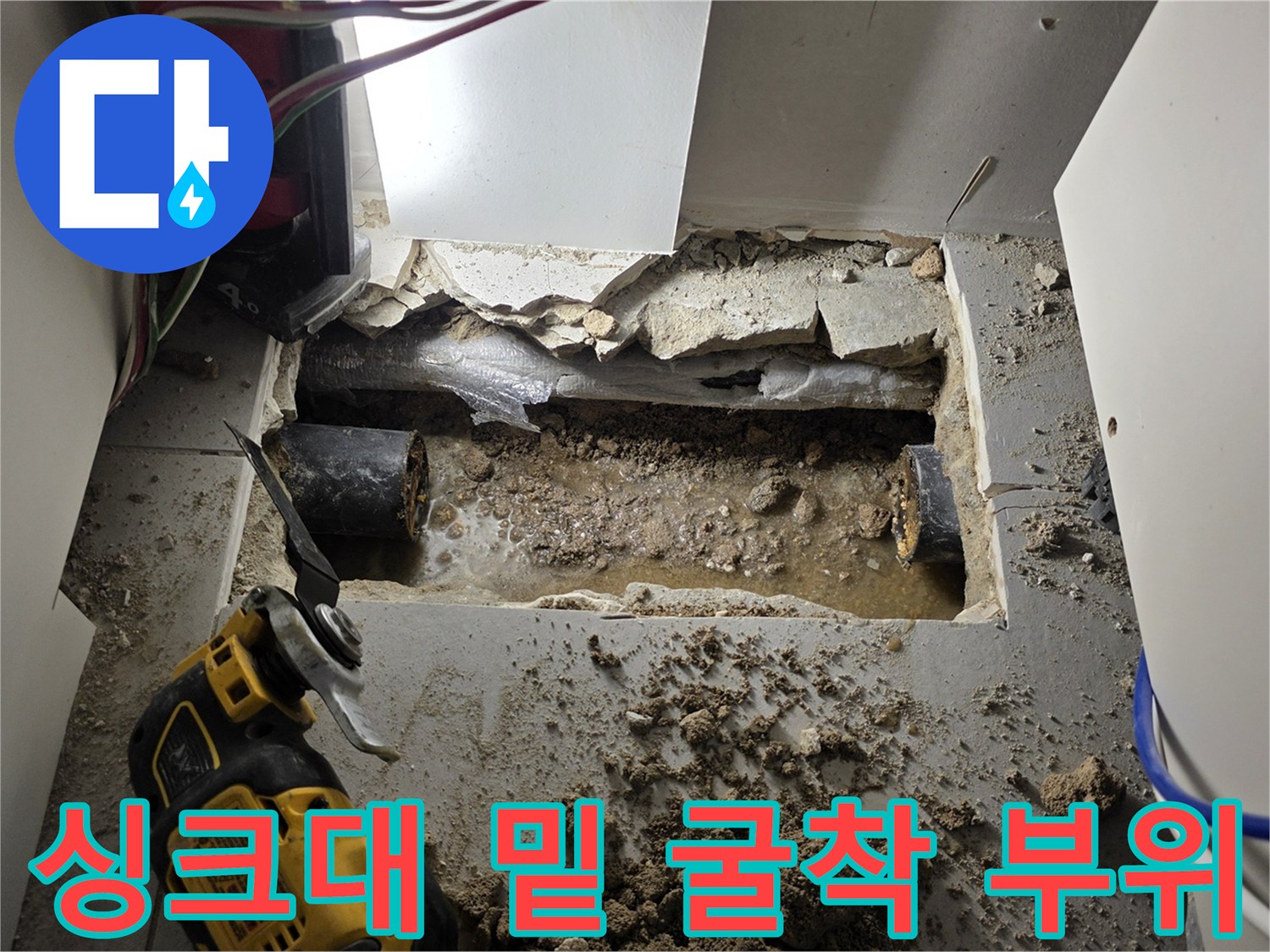 공사 중인 싱크대 아래 바닥의 젖은 배관과 주변 자재들