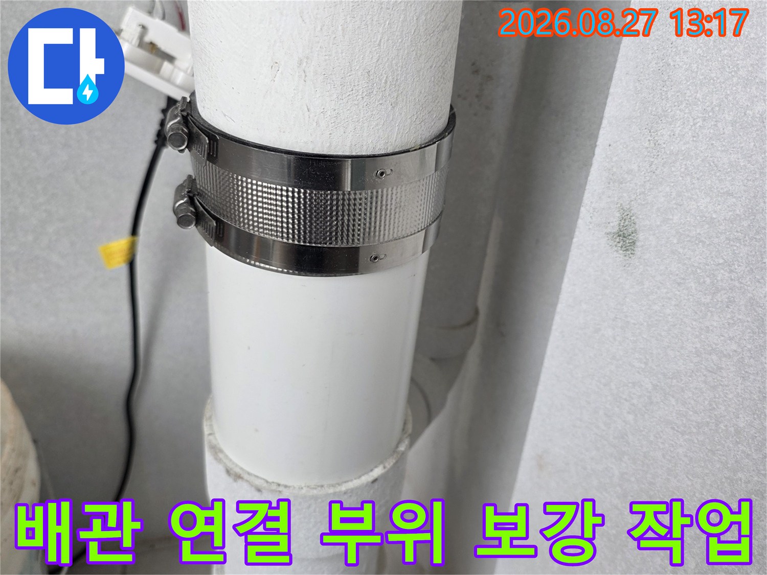 하얀색 우수관에 금속 클램프를 사용하여 틈새를 막는 공사 모습입니다.