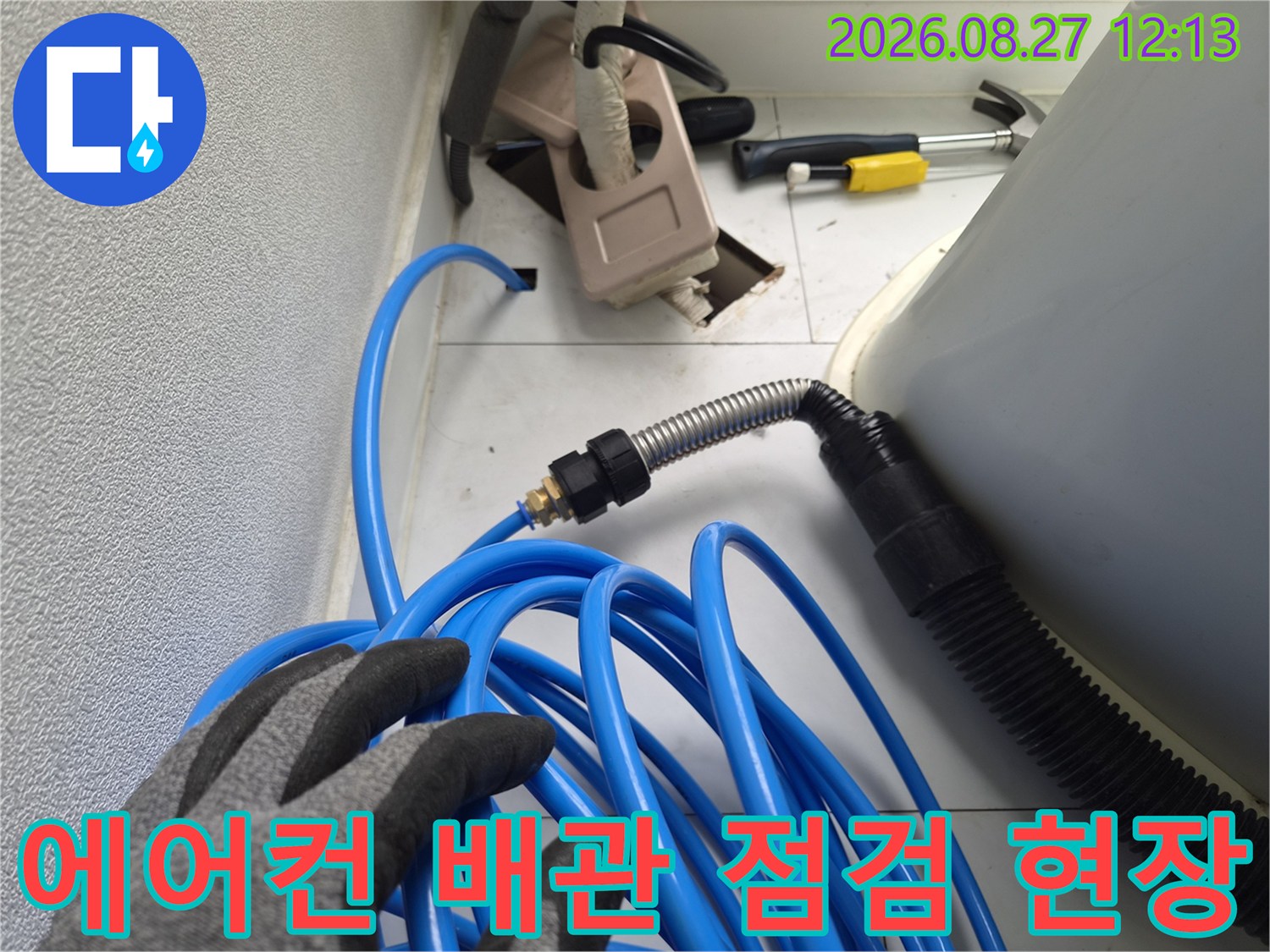 에어컨 드레인 배관의 이물질을 제거하기 위해 준비된 파란색 호스와 장비들입니다.