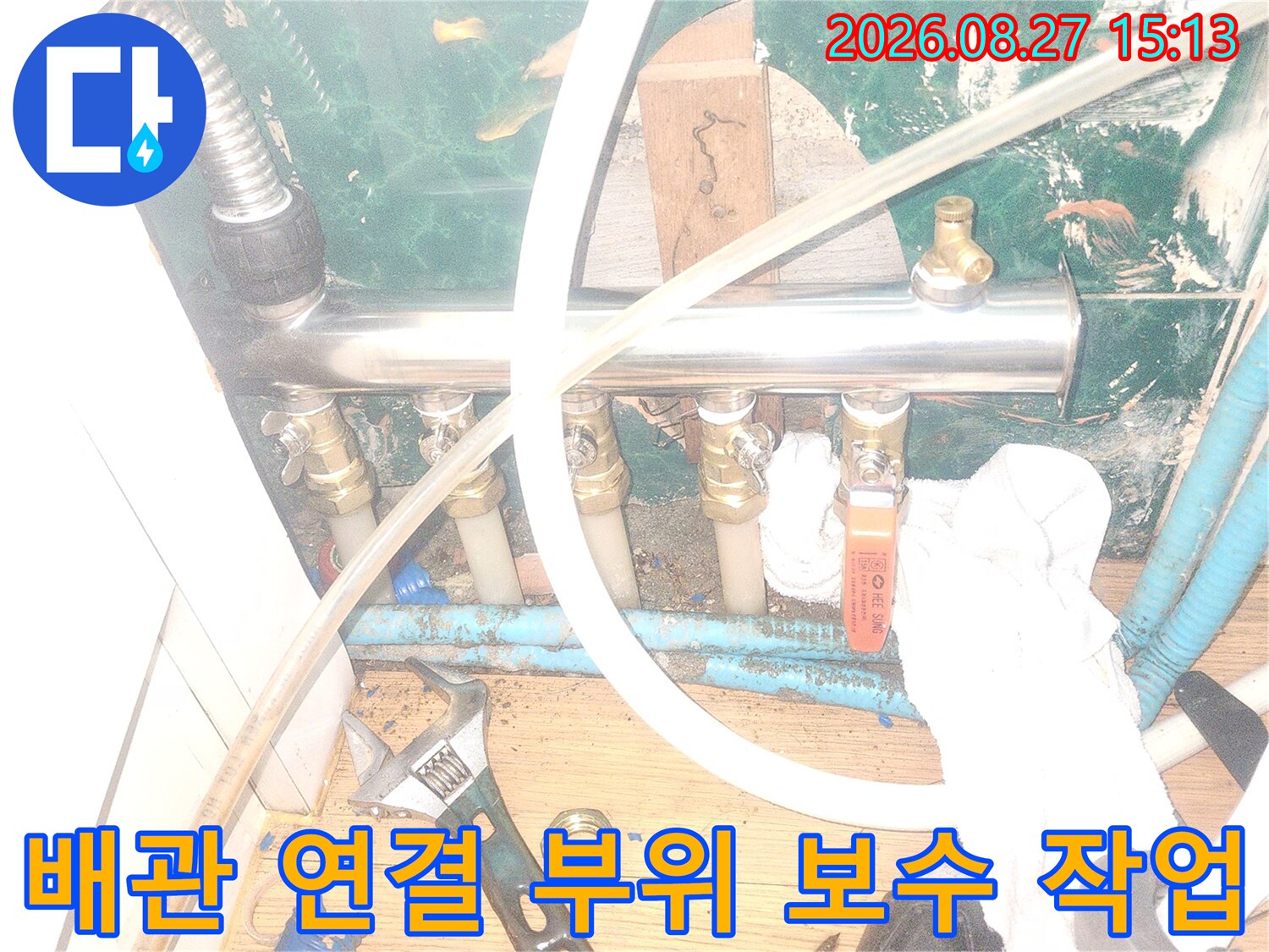 스패너를 사용하여 분배기 밸브를 조이는 배관 수리 장면