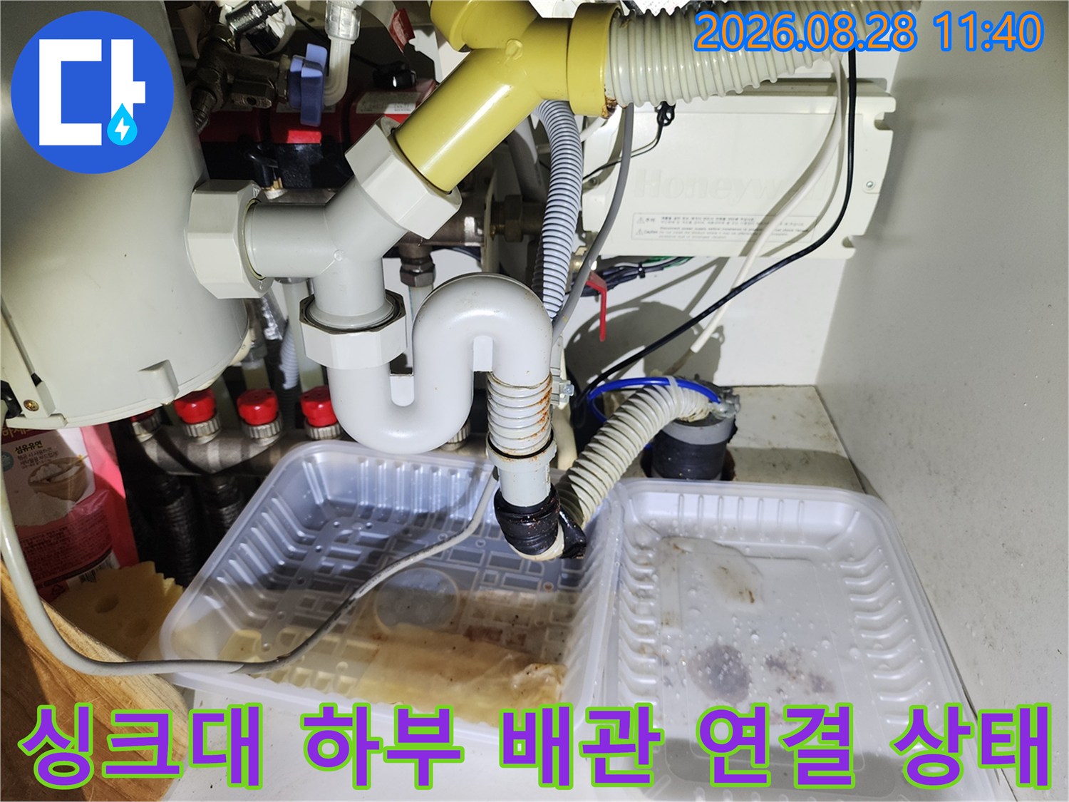 싱크대 아래쪽 흰색 PVC 배관과 주름진 호스의 접합 부위