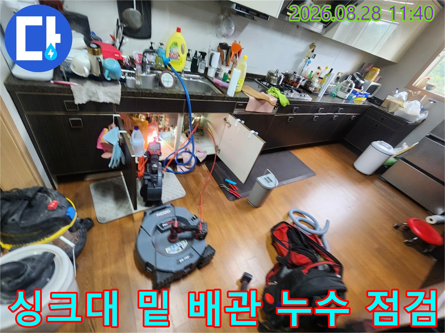 싱크대 하단부의 복잡한 배장 연결 부위와 점검 장비가 보이는 사진입니다.