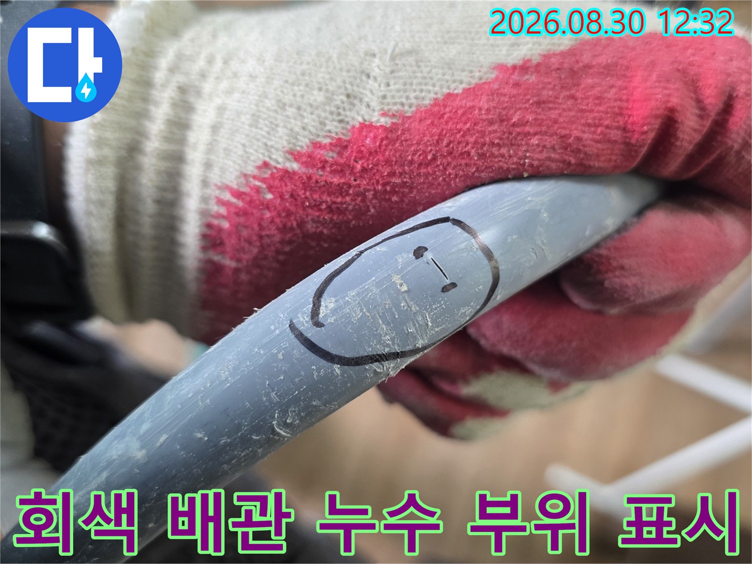 작업자의 장갑 낀 손이-회색 배관의 파손된 부분을 가리키고 있습니다