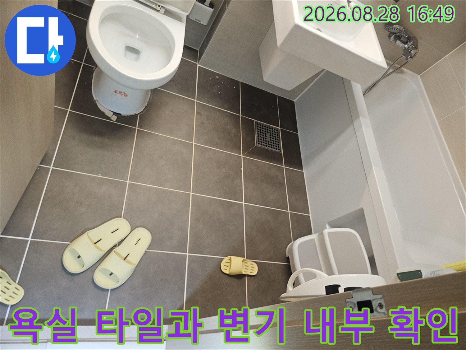 변기 주변의 회색 타일 벽면과 배수구 근처 상세 사진