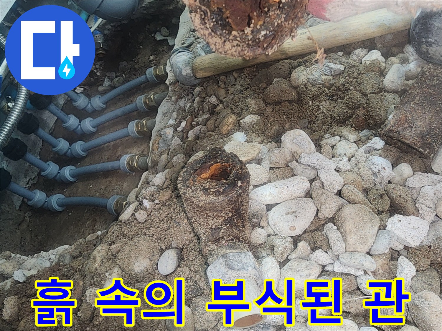 자갈과 흙 사이에 드러난 노후된 분배기 배관