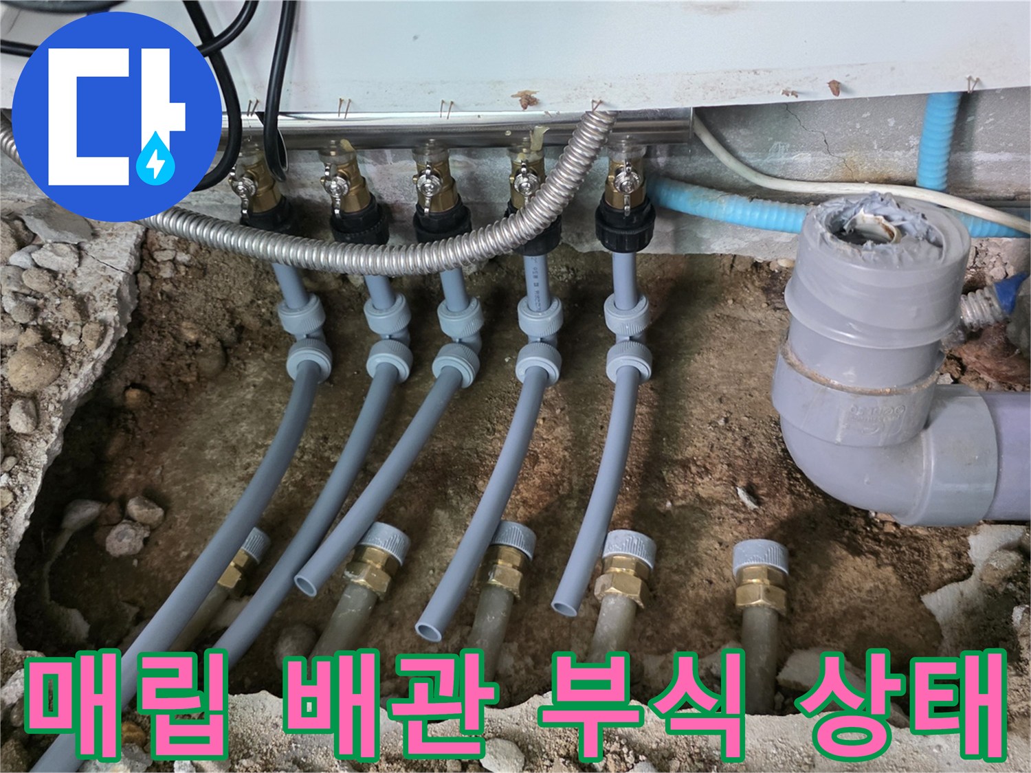 흙과 자갈 사이로 보이는 노후된 분배기 및 하수관 연결부
