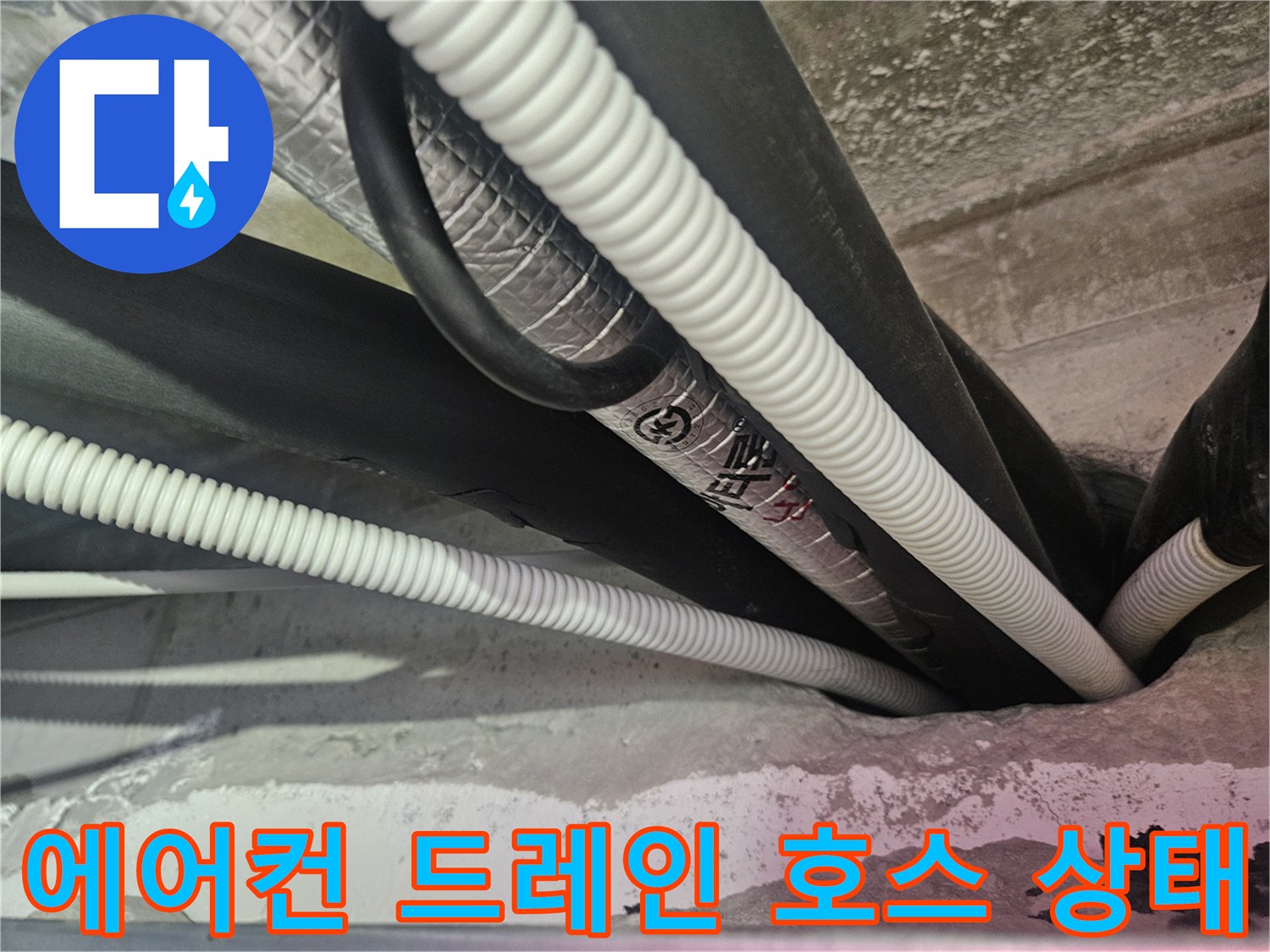 천장 텍스 사이로 보이는 하얀색 주름관과 검은색 배관의 연결 부위