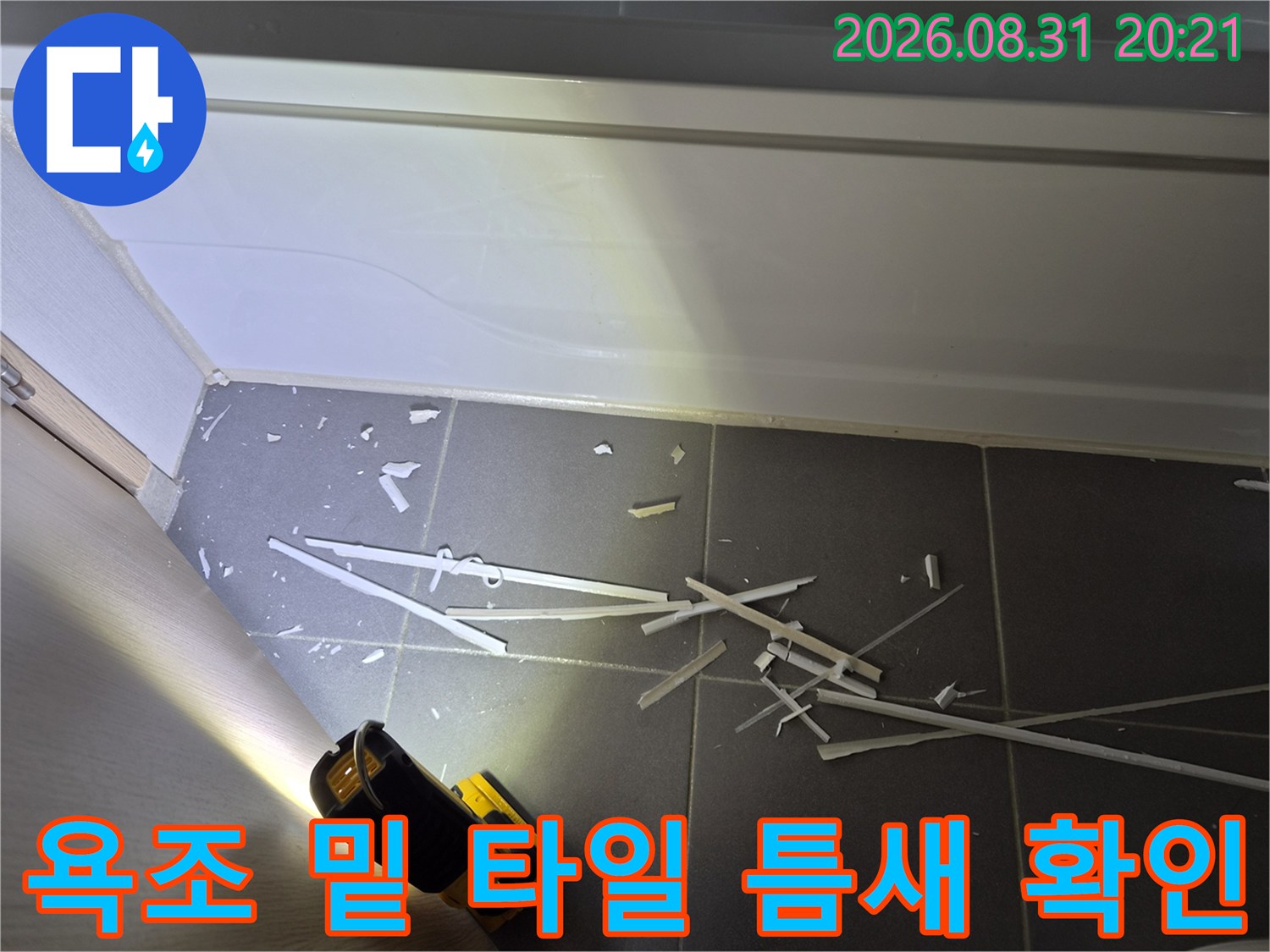 손전등 조명으로 비춰진 욕조 하부의 타일 및 경계면