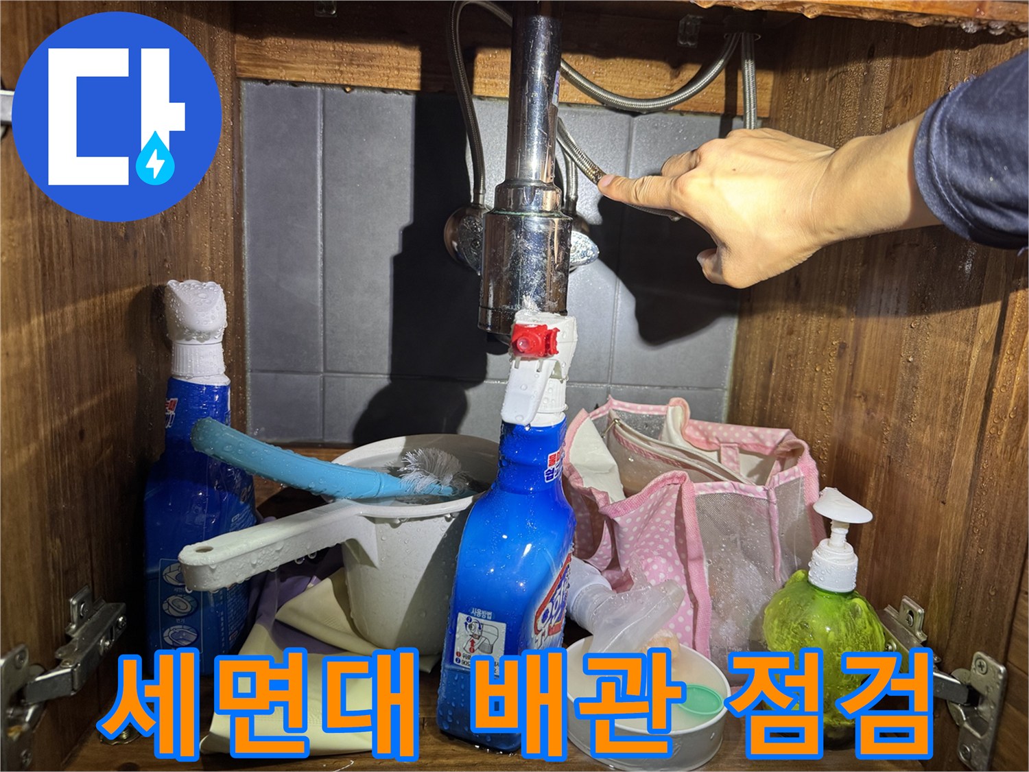 세면대 아래쪽 수전 연결 부위를 손으로 점검하는 모습